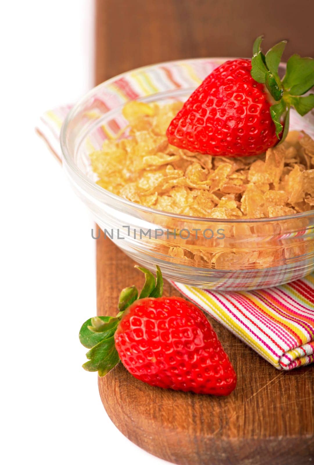 Bowl of tasty crispy corn flakes with milk and strawberries on white