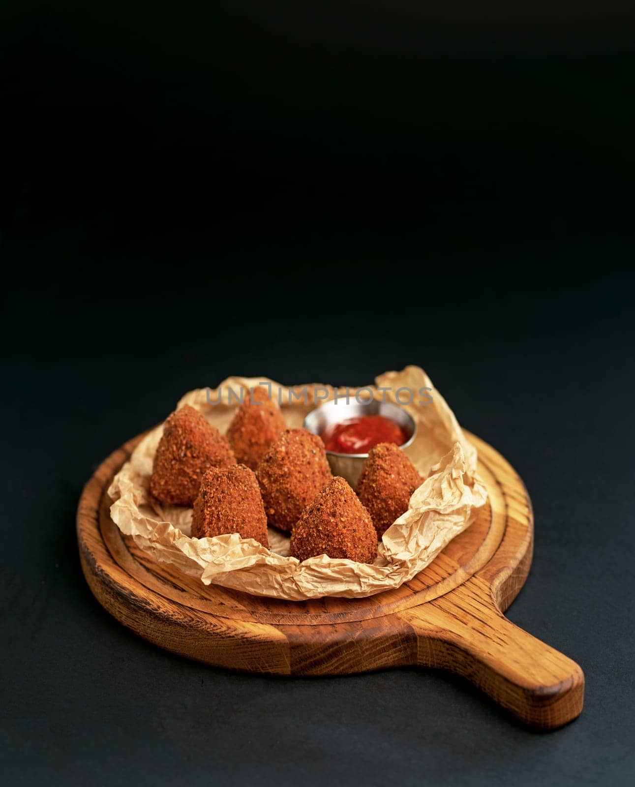 Deep fried crispy Camembert with cranberry sauce in a decorative pan on wooden background.