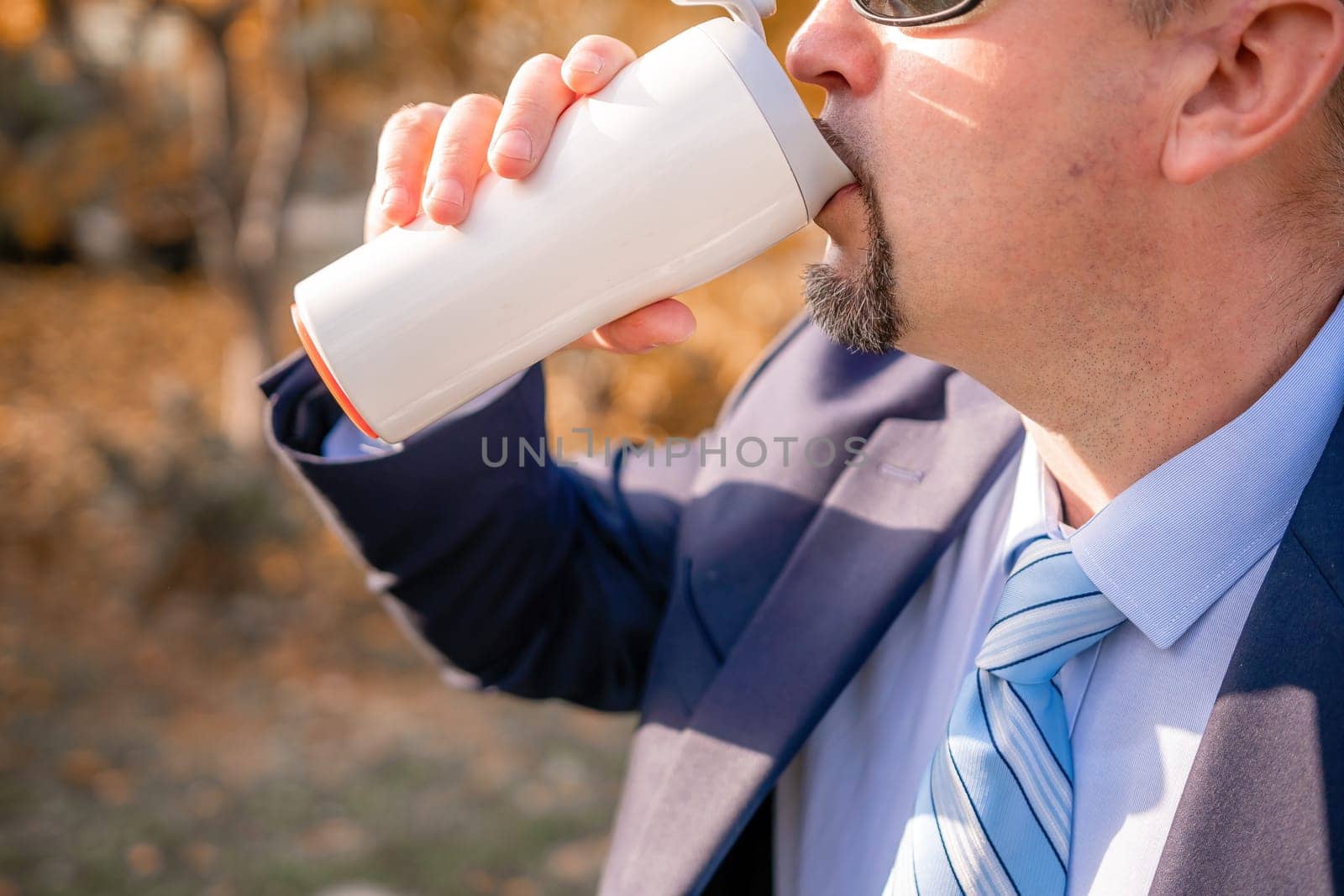 Mature entrepreneur drink coffee in autumn park. Senior executive rest in city park.