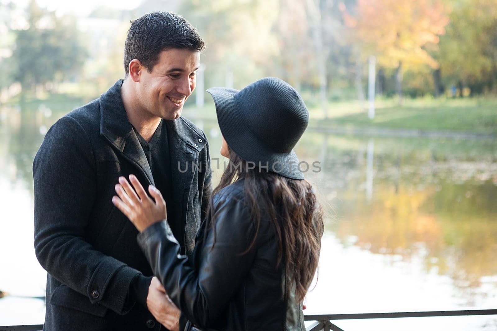 Beautiful gourgeous couple walking in autumn park near a lake