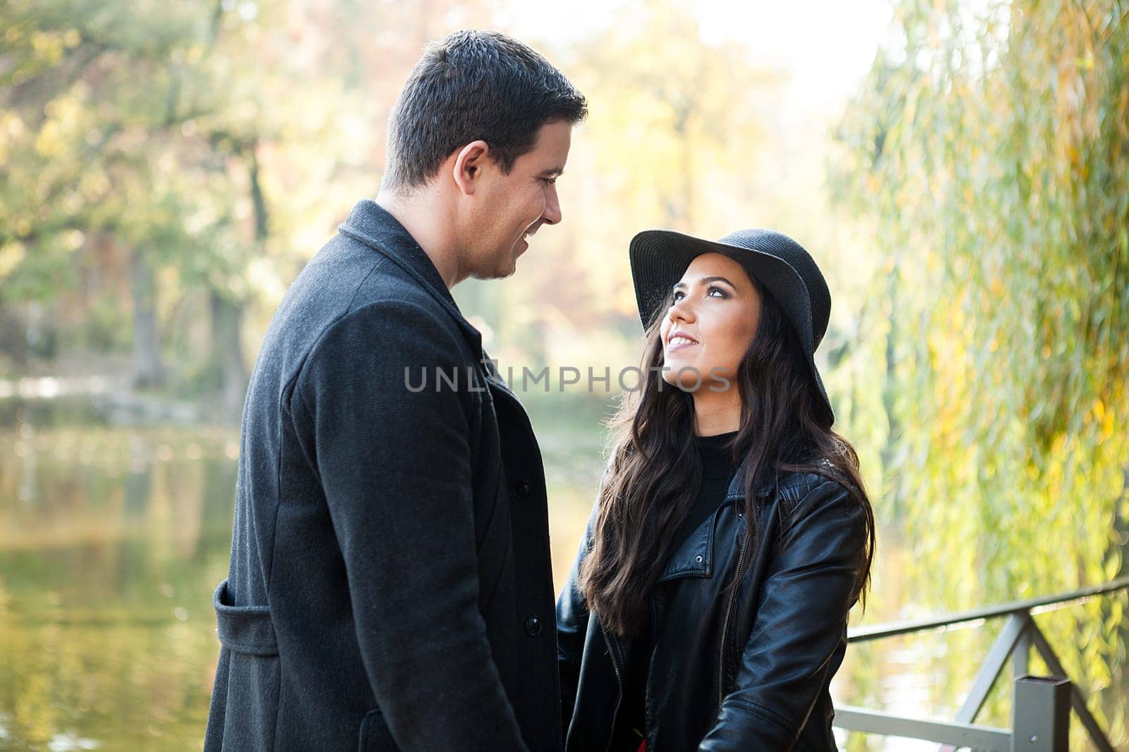 Beautiful gourgeous couple walking in autumn park near a lake