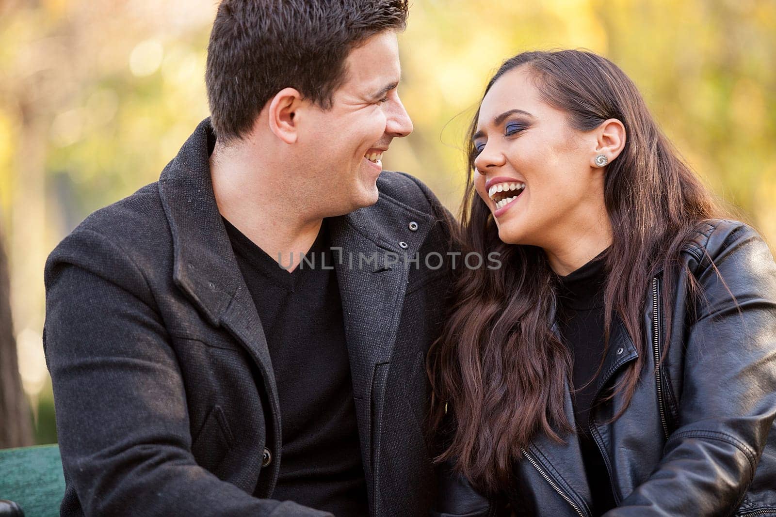 Close up of beautiful in love couple sitting on a bench in autumn park