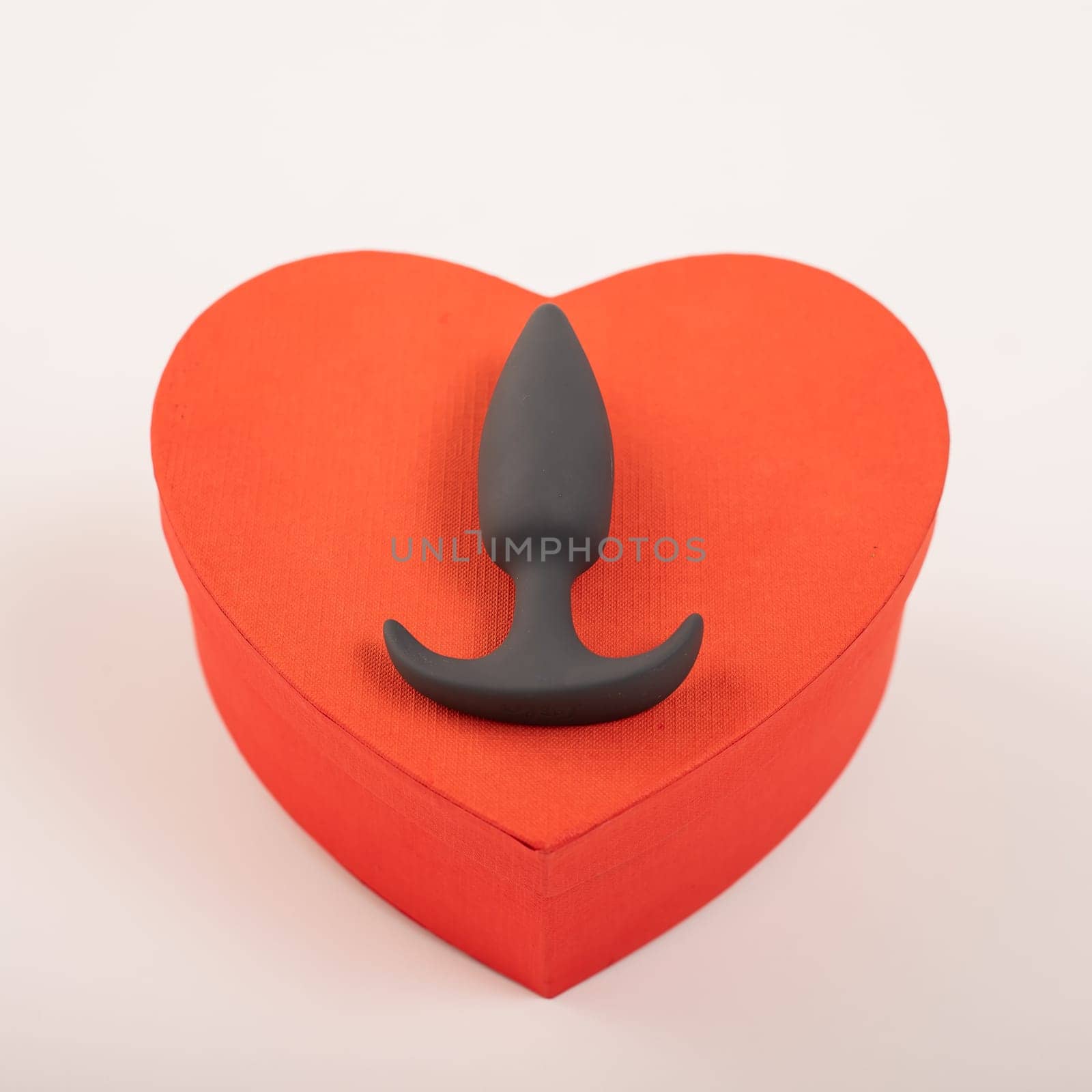 Heart-shaped box and butt plug on a white background. Love on February 14