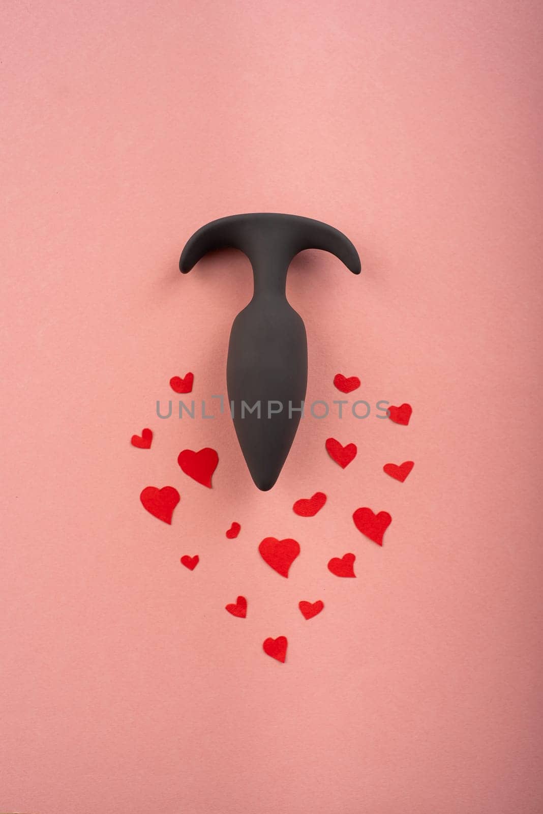 Butt plug and hearts on a pink background. Love symbol for February 14.