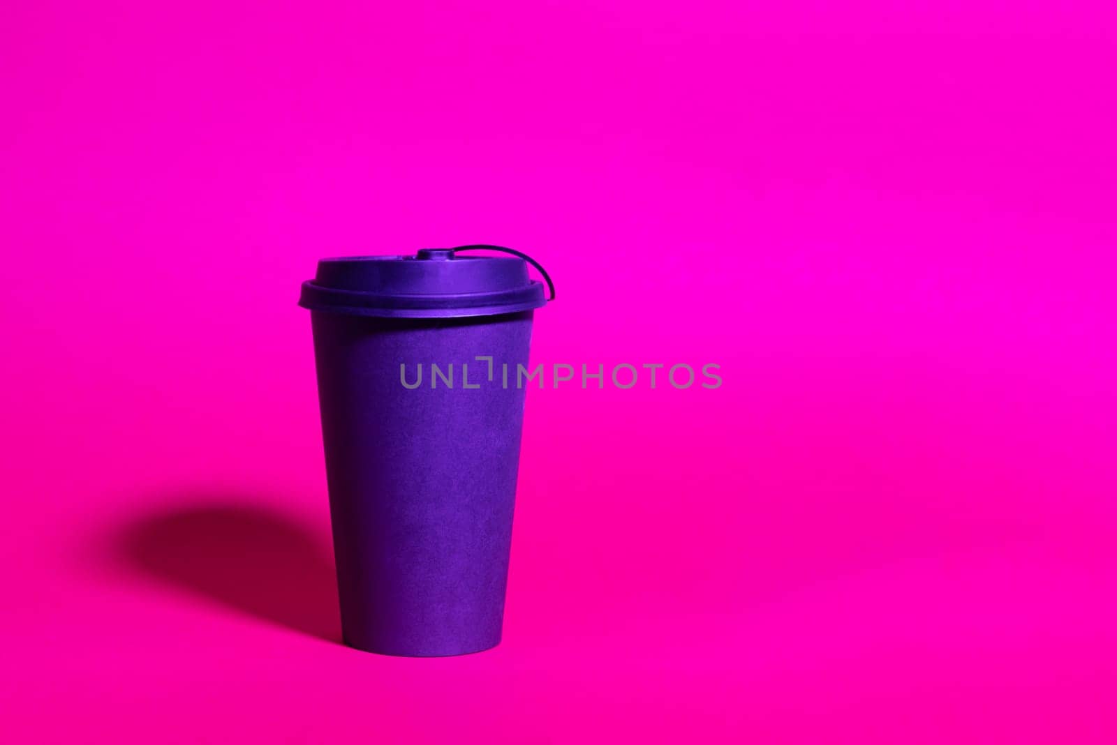 Mock up of black paper coffee cup ready to go, trend duotone neon ultraviolet color lightning. Colored light, creative trendy effect
