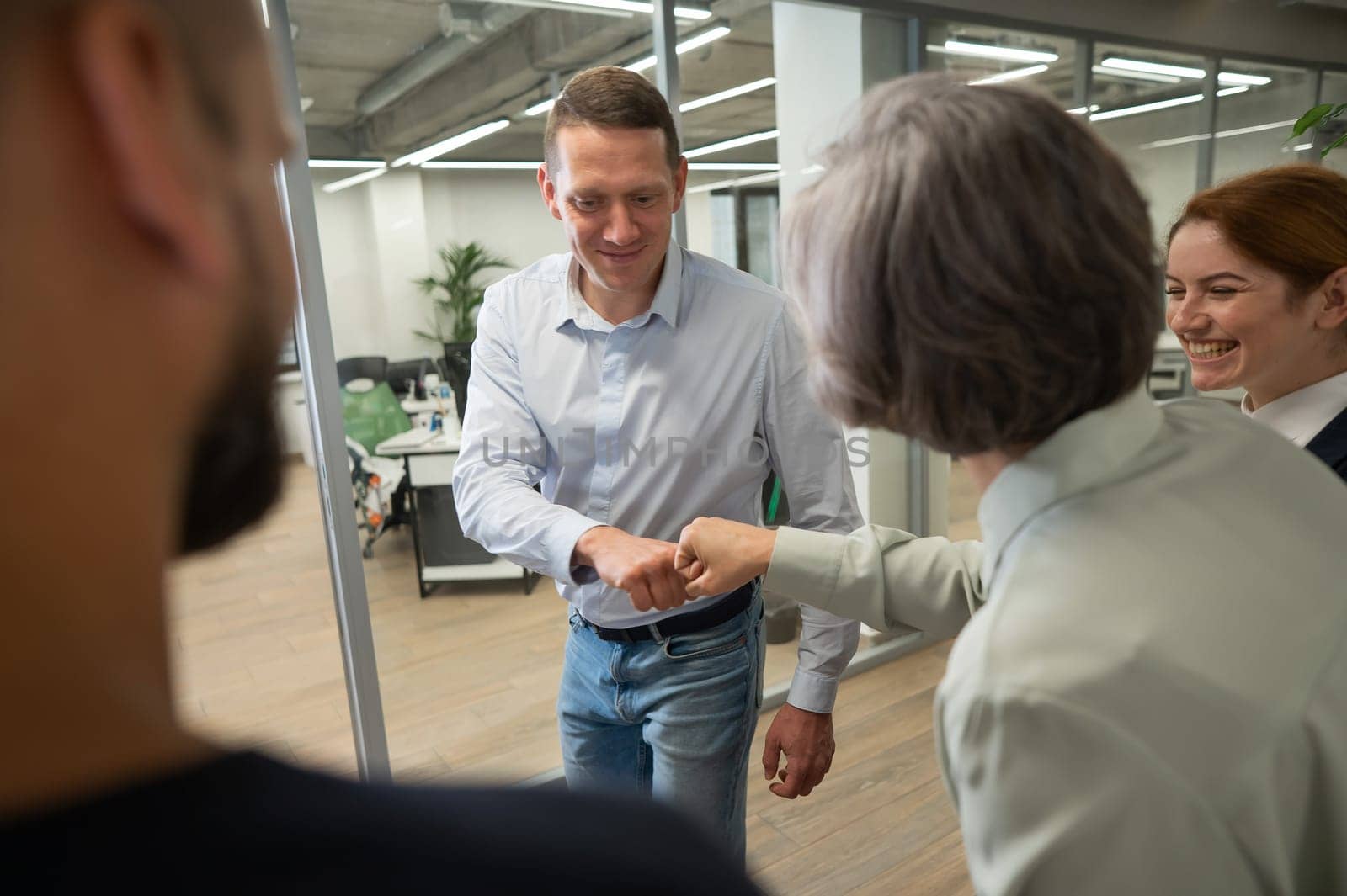 Caucasian man bumping his fists with colleagues as a sign of success. by mrwed54