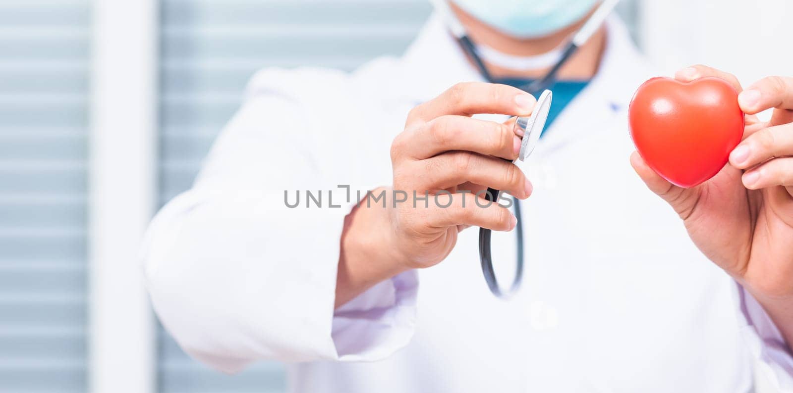 Doctor Day Concept. Doctor man wearing white coat standing holds his stethoscope on hand for listening examining red heart, person showing medical equipment, healthcare close up view