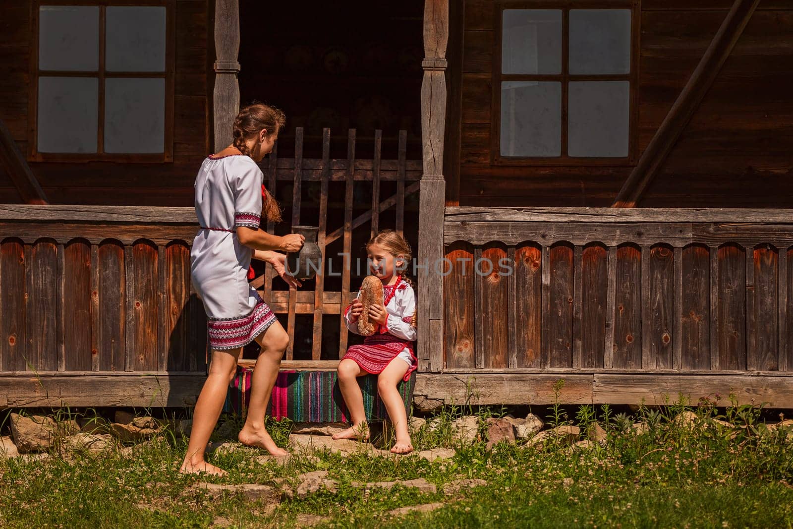 mother and daughter in Ukrainian folk dresses on the threshold of the house.