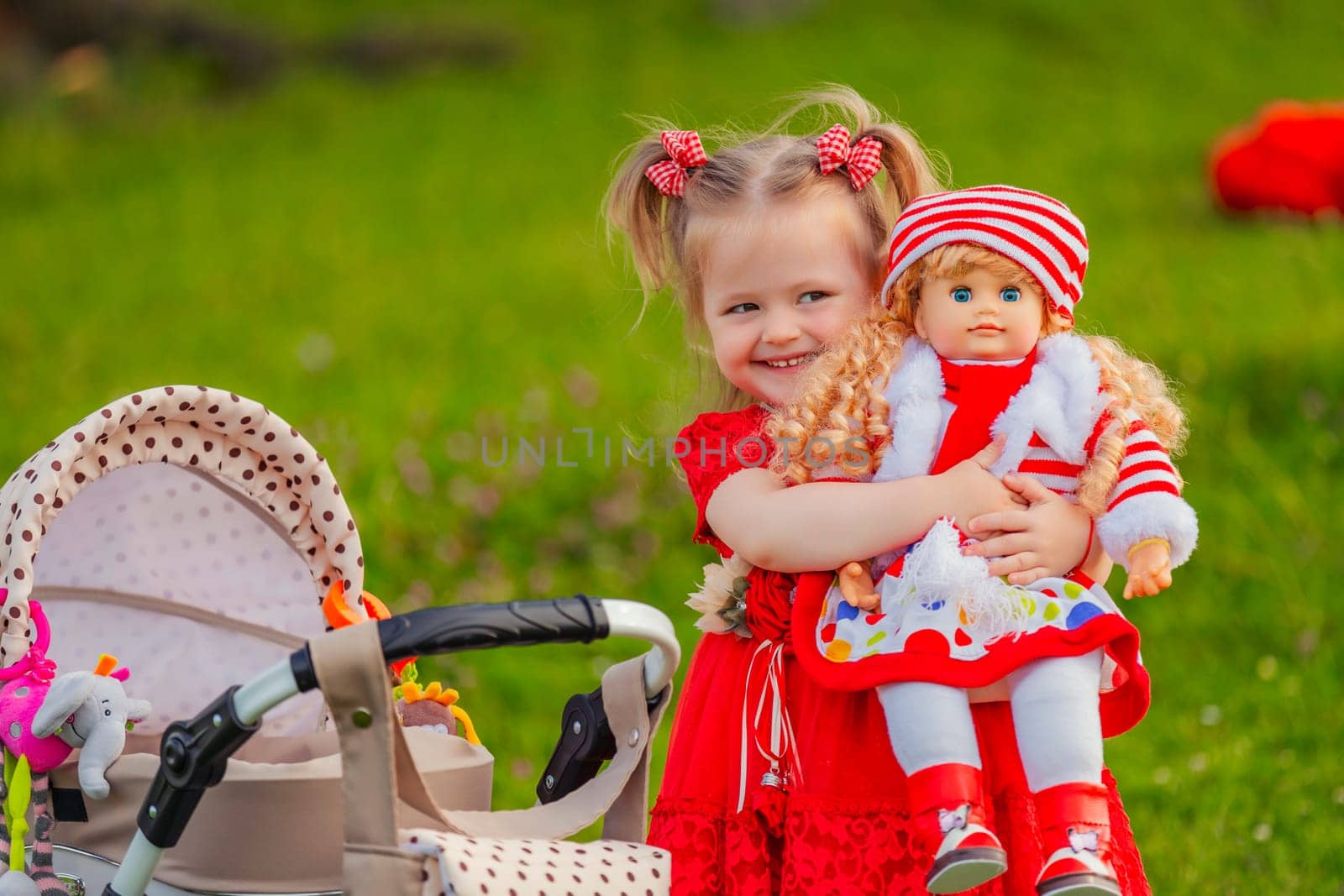 The girl plays with a doll in nature, holding her in her arms