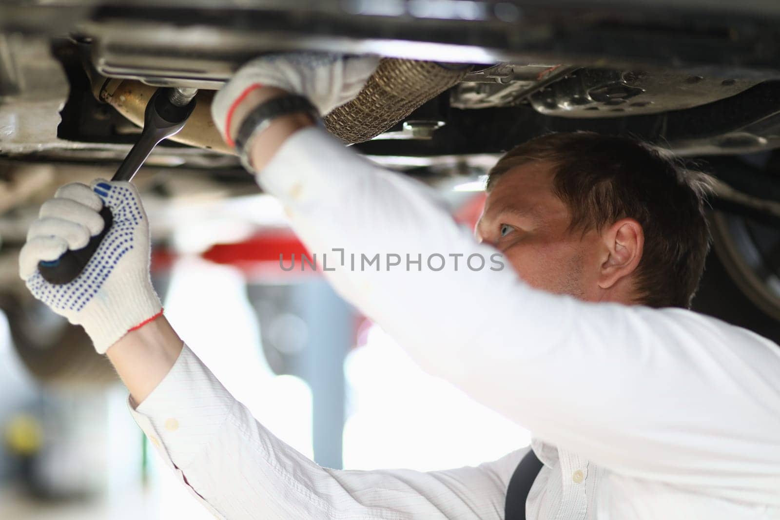 Auto mechanic checks running gear of car at service station. Car mechanic fixing problem with car and problem solving concept