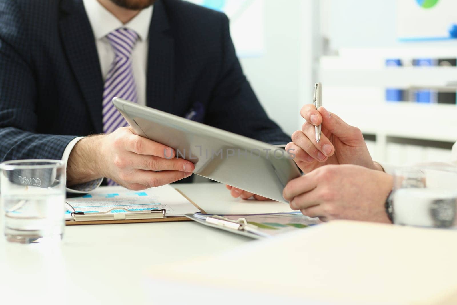 Businessman analyzes graph using touchpad of digital tablet. Business people reporting on financial charts and summarizing financial growth