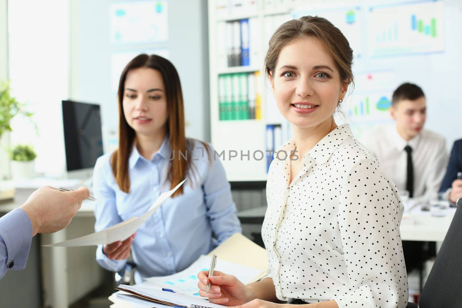 Young beautiful business woman writes in a notebook during seminar. Portrait of female employee listening to executive at corporate meeting and taking notes concept