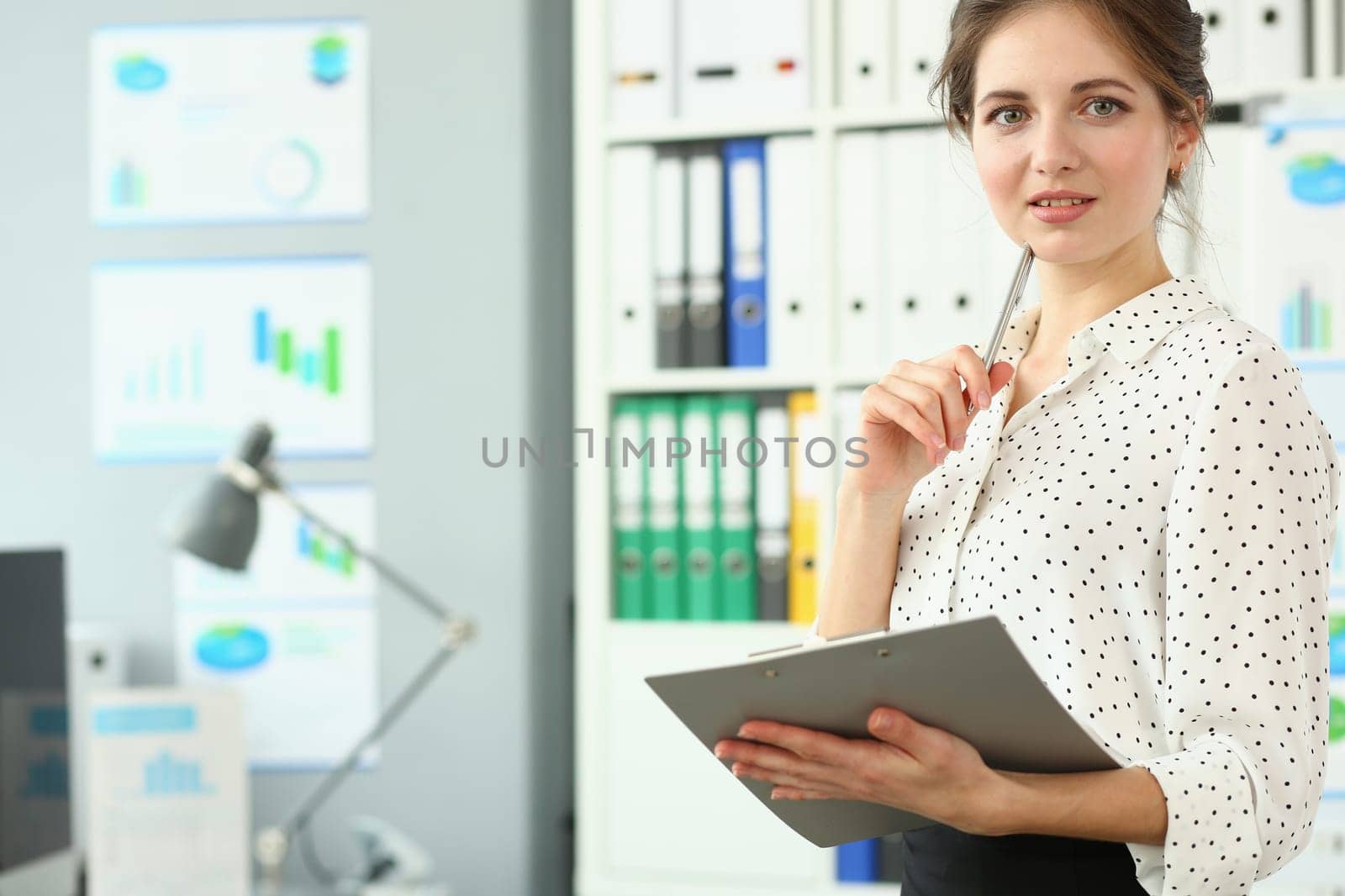 Portrait of smart pensive business woman holding pen and documents in office. Business consultant manager or boss