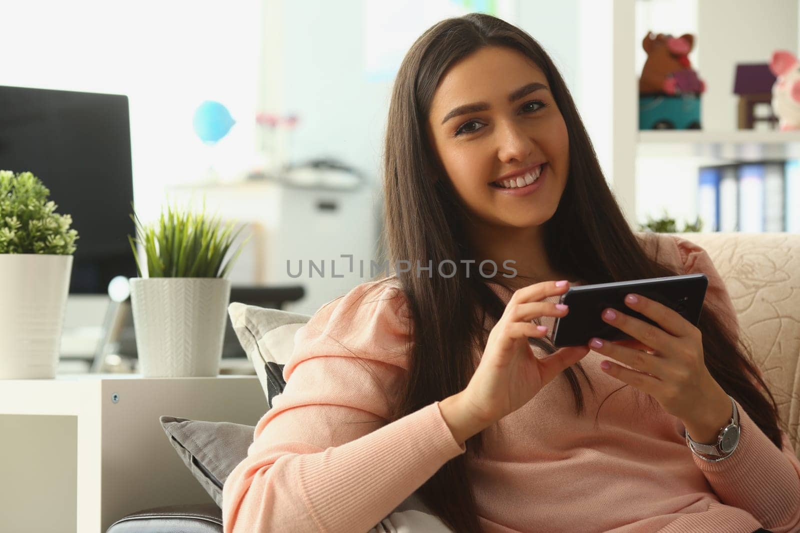 Relaxed smiling woman on sofa at home using smartphone and texting. Chat communication and mobile apps concept