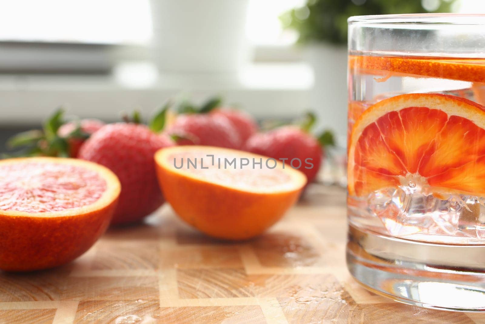 Red orange punch with strawberry and orange in glass with ice. Homemade chilled alcoholic cocktail closeup