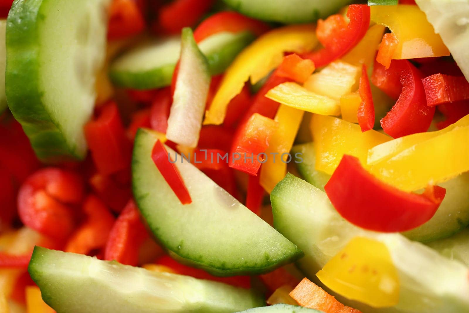 Top view macro sliced cucumber red and yellow peppers. Vegetable fresh juicy healthy salad concept