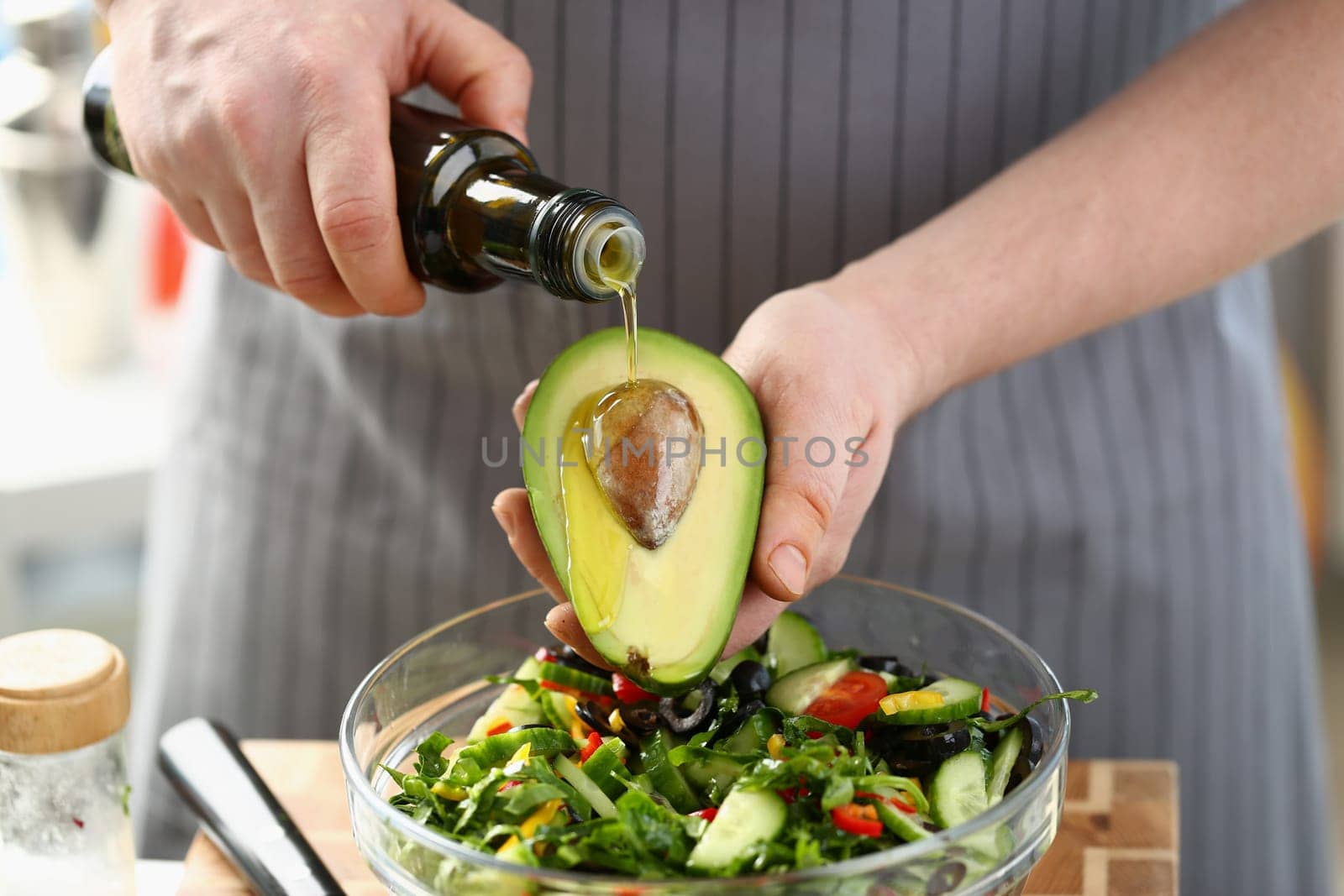 Chef prepares a salad of fresh green vegetables and avocado with butter. Cooking healthy diet or vegetarian food concept