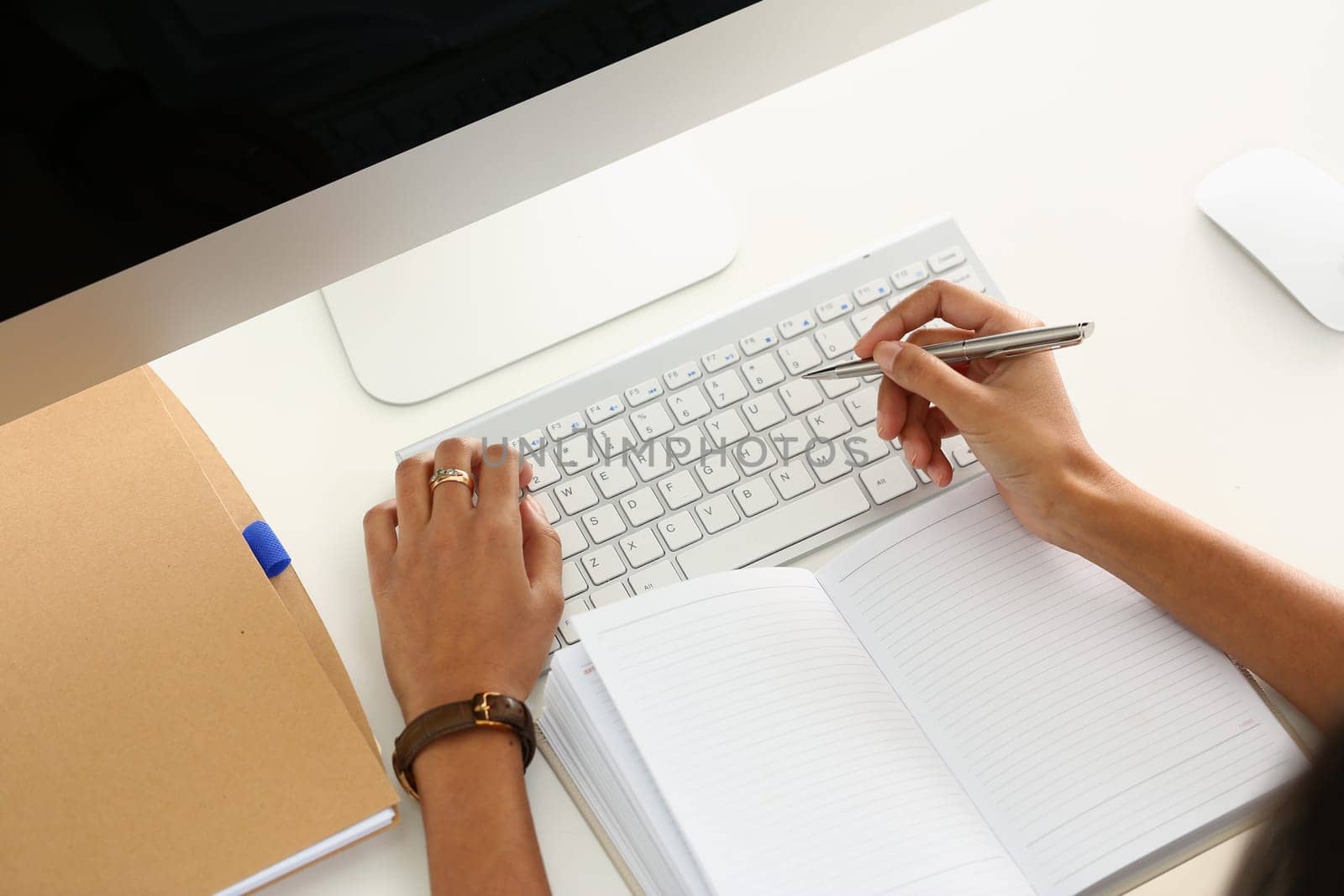 Business person writes with pen in diary on laptop keyboard in office. Business and educational concept