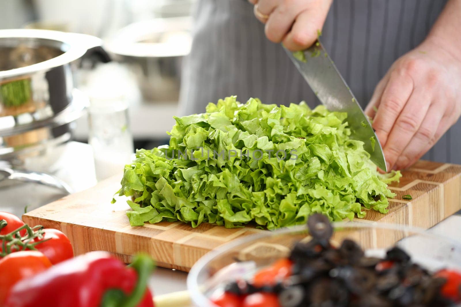 Hands of cook are preparing vegetable salad closeup. Cutting lettuce leaves and preparing vegetarian food