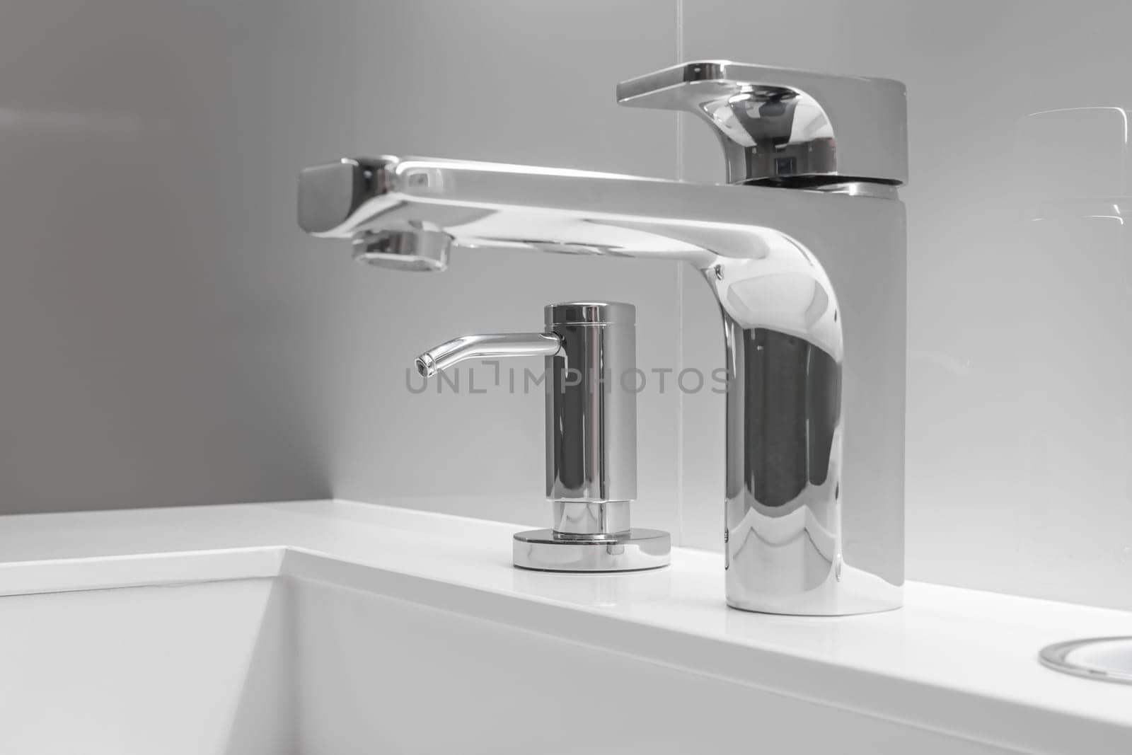 Close-up of white sink with large and small taps for filtering drinking running water. Concept of clean drinking water and high-tech purification system.