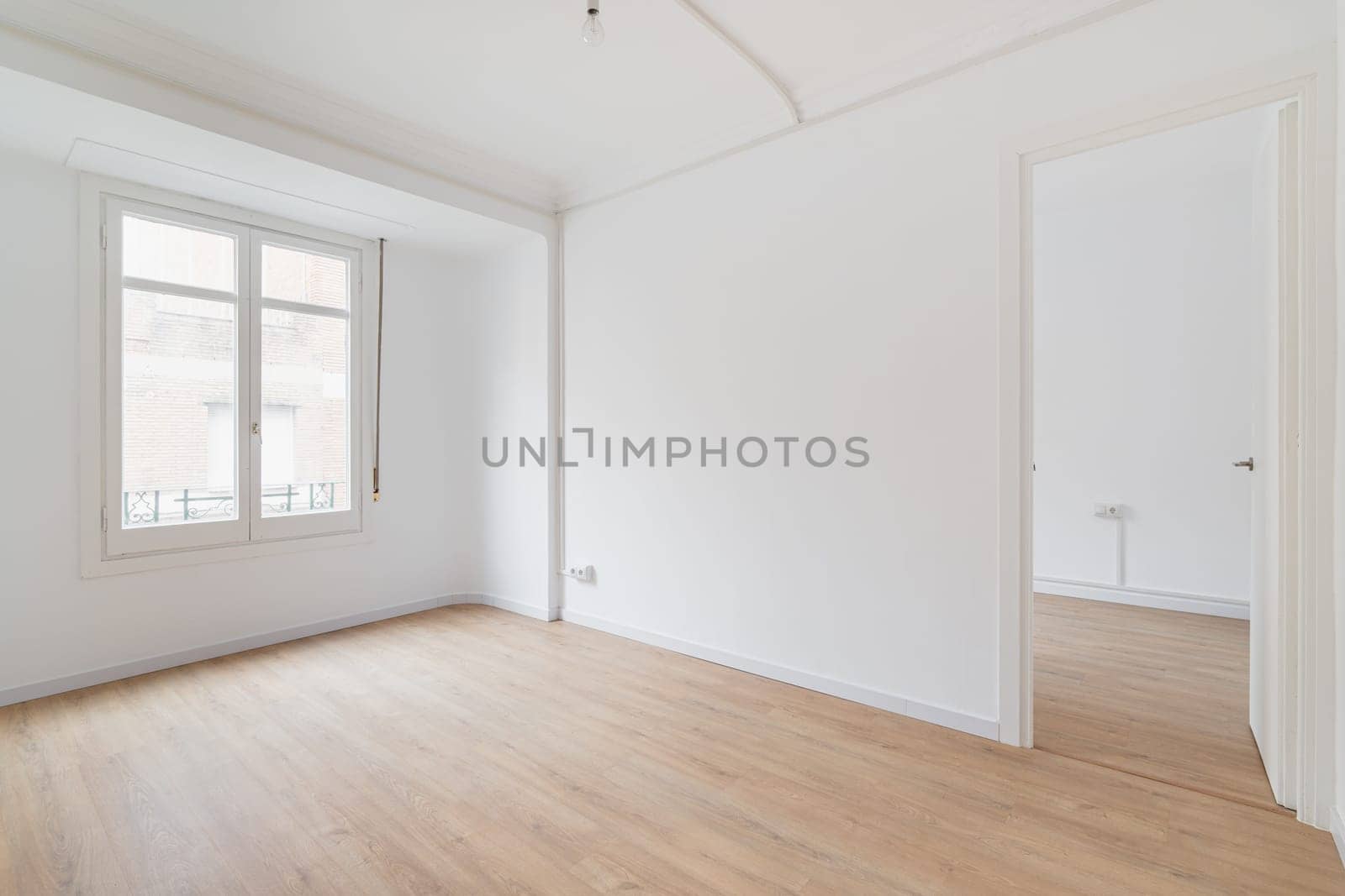 Bright white spacious unfurnished apartment with an window and wooden textured laminate. Concept of modern building or moving to new apartment. Interior design renovation.