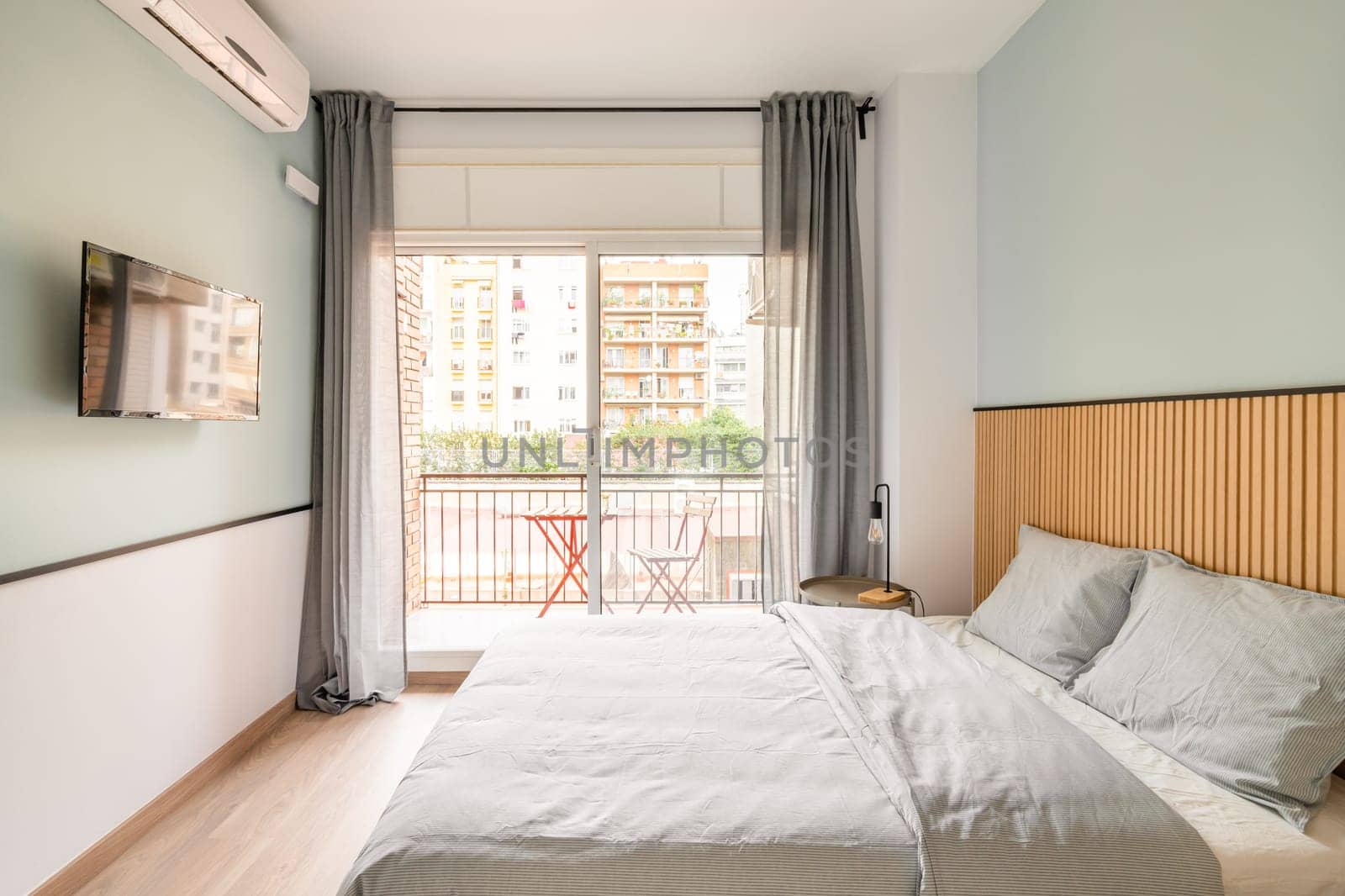 Spacious bright room with bed, large opening on entire wall with sliding plastic doors and access to balcony. Room has table with chair, air conditioning and TV for pleasant leisure