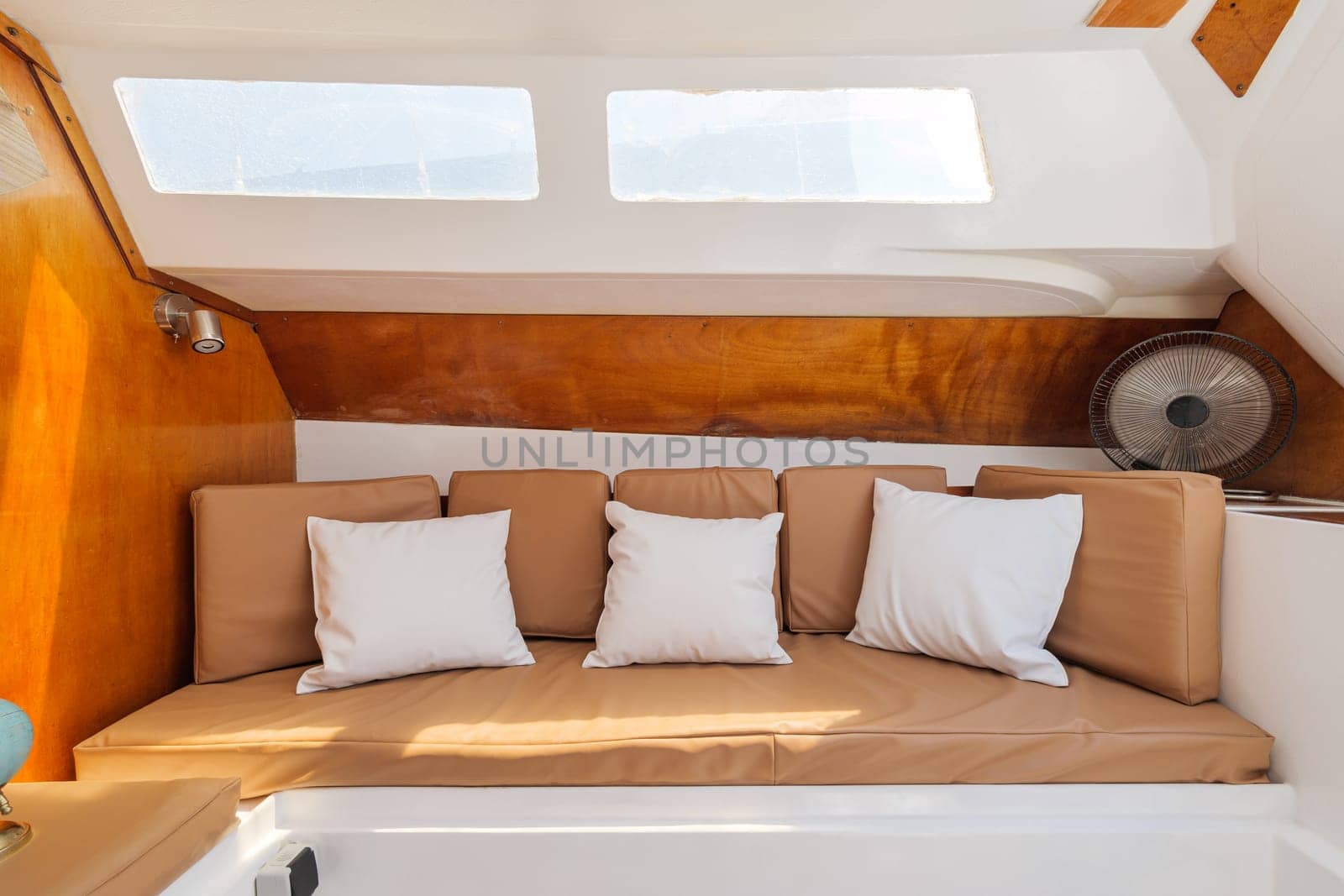 Genuine calf brown leather sofa with cushions in cozy yacht with fan while traveling. Concept of a vacation on your own ship in warm countries by apavlin
