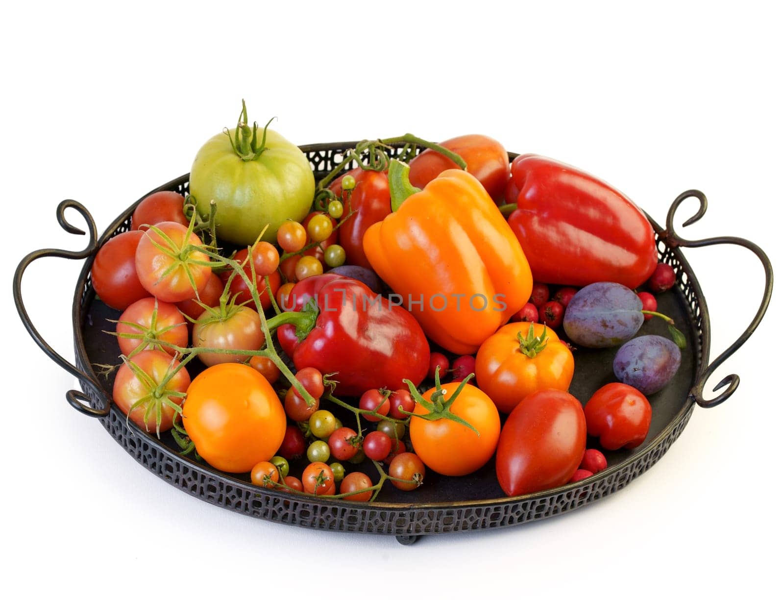 Tomatoes of various varieties and sizes on an iron tray on a wooden table. by aprilphoto