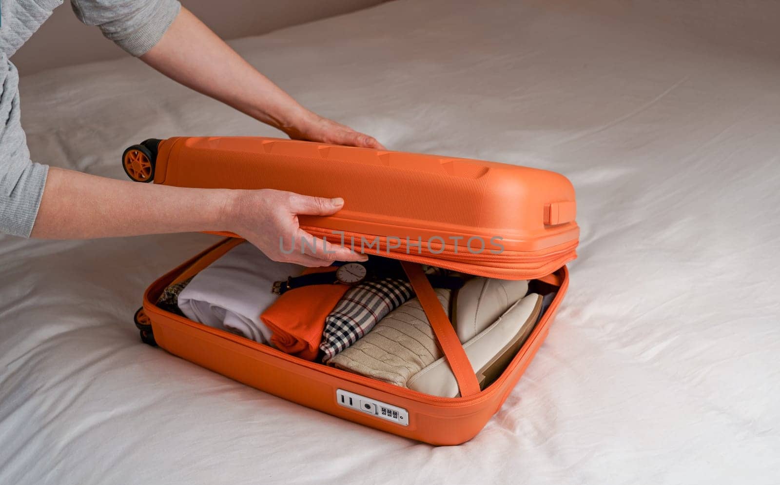 a woman puts clothes in a suitcase on the bed to prepare for a weekend trip. Pack your luggage and check if you forgot anything before your trip. by aprilphoto