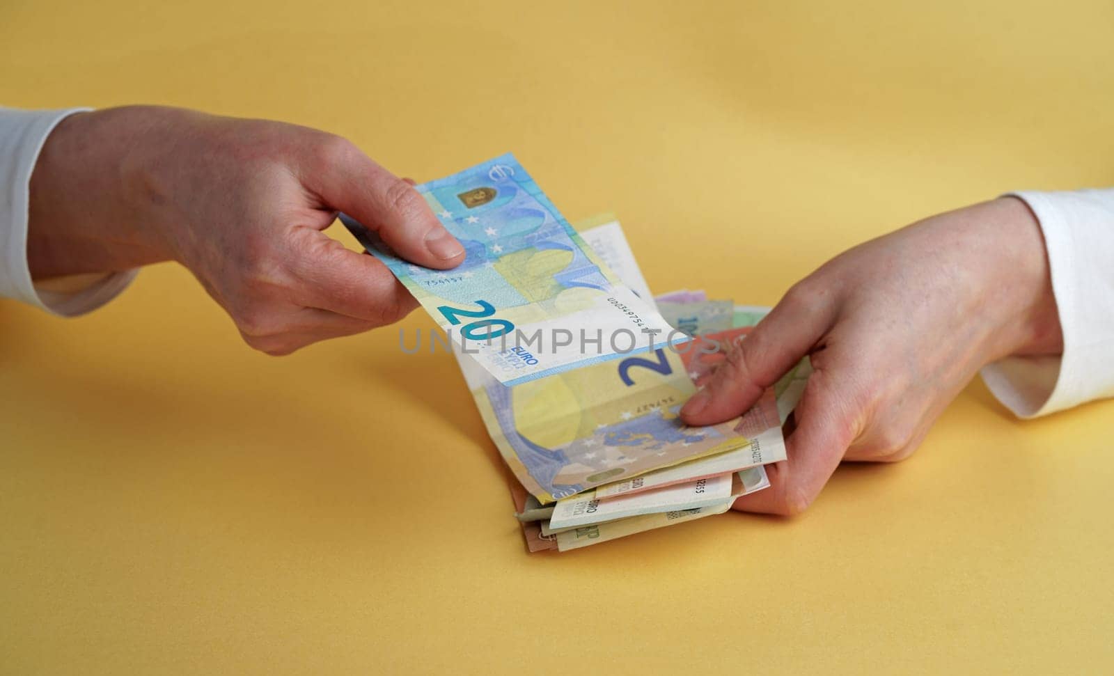 Euro Money. Female hands holding euro banknotes on a yellow background.