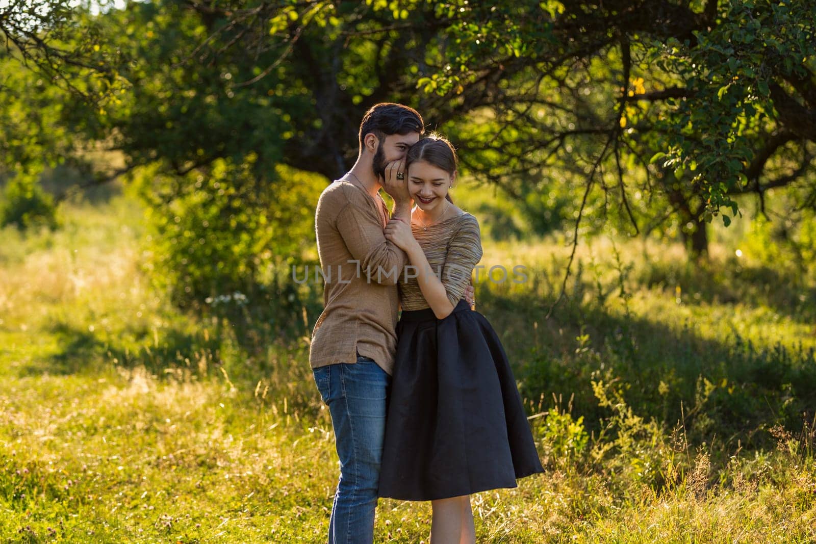 man tells in his ear the secret of his girlfriend walking in the park