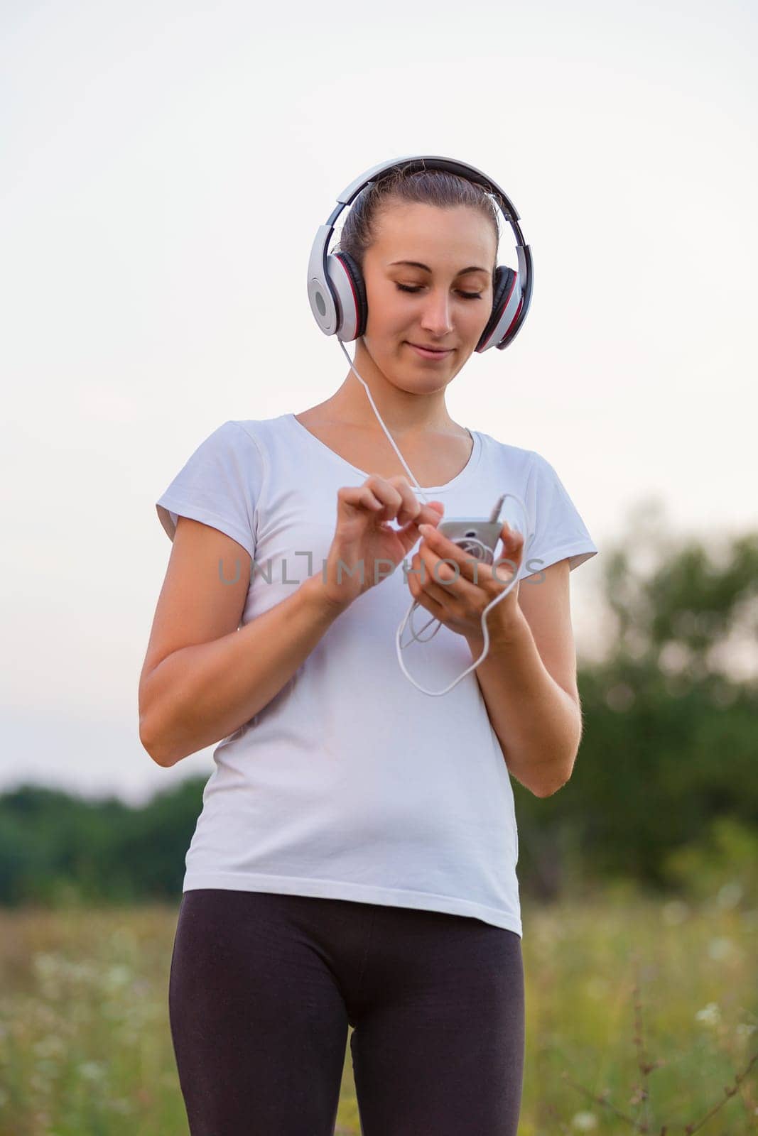 woman in headphones outdoors listening to music using phone