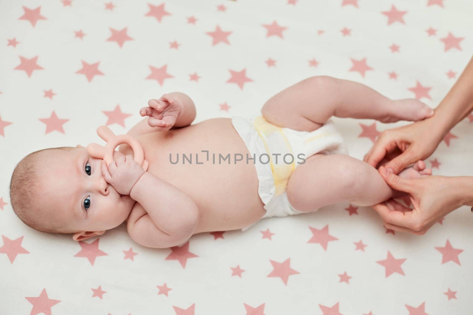 Mom or therapist giving massage to baby at home. massage of baby legs by mother.