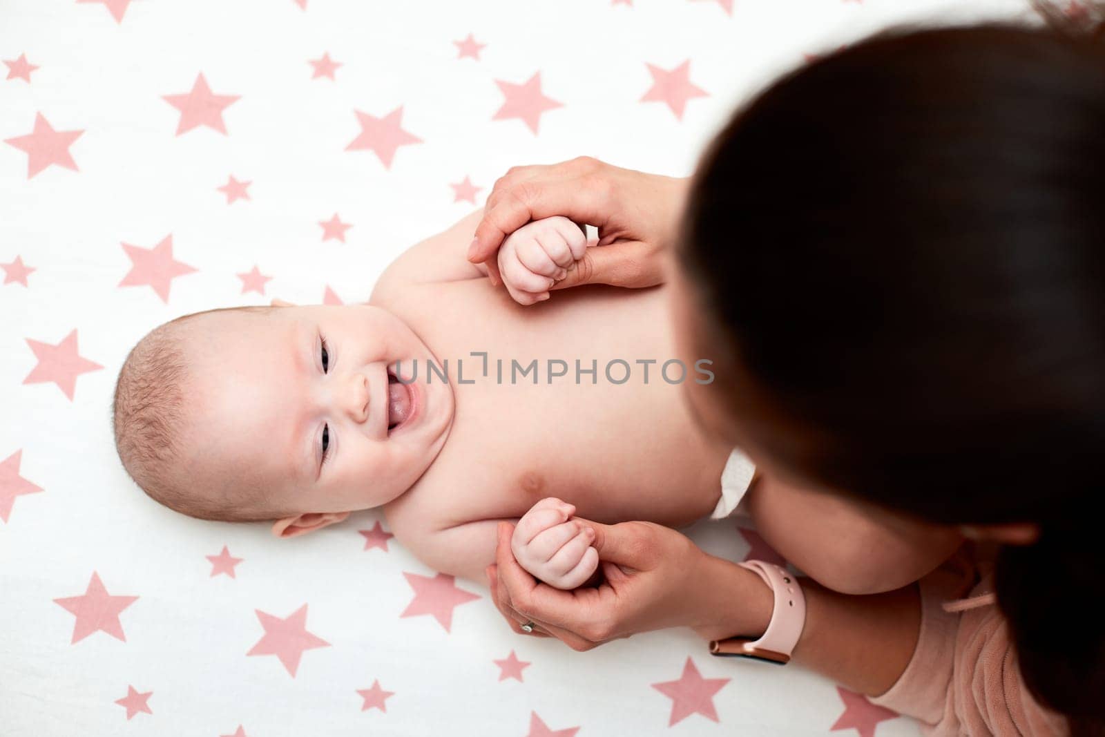 Loving mother playing with baby girl. top view. Mom giving massage to child