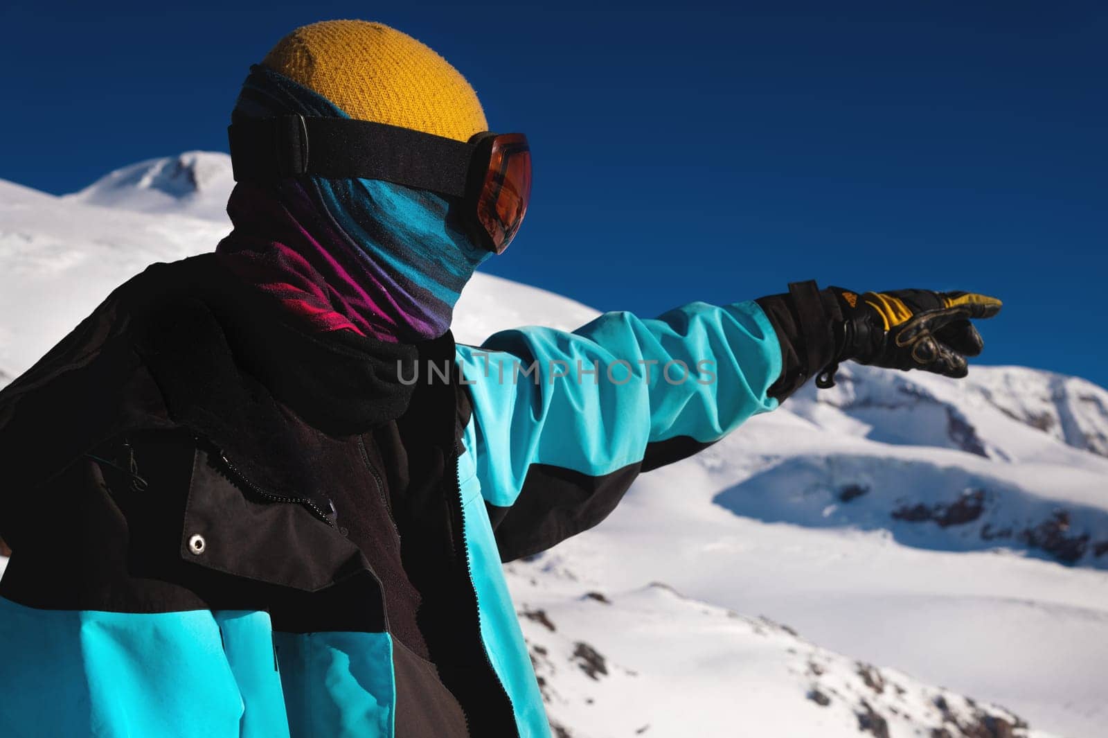 Sportsman pointing with his hand while skiing on a snowy slope. A traveler, a tourist, pointing his hand somewhere in the direction of the mountains. Winter sports activity.