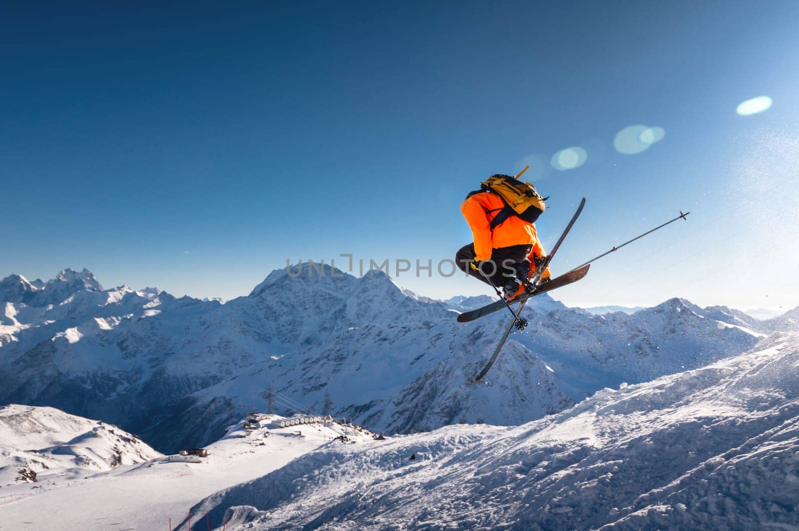 The skier jumps on the background of the blue sky and snow-capped mountains. freestyle skier performs helicopter with crossed skis simultaneously with full rotation by yanik88
