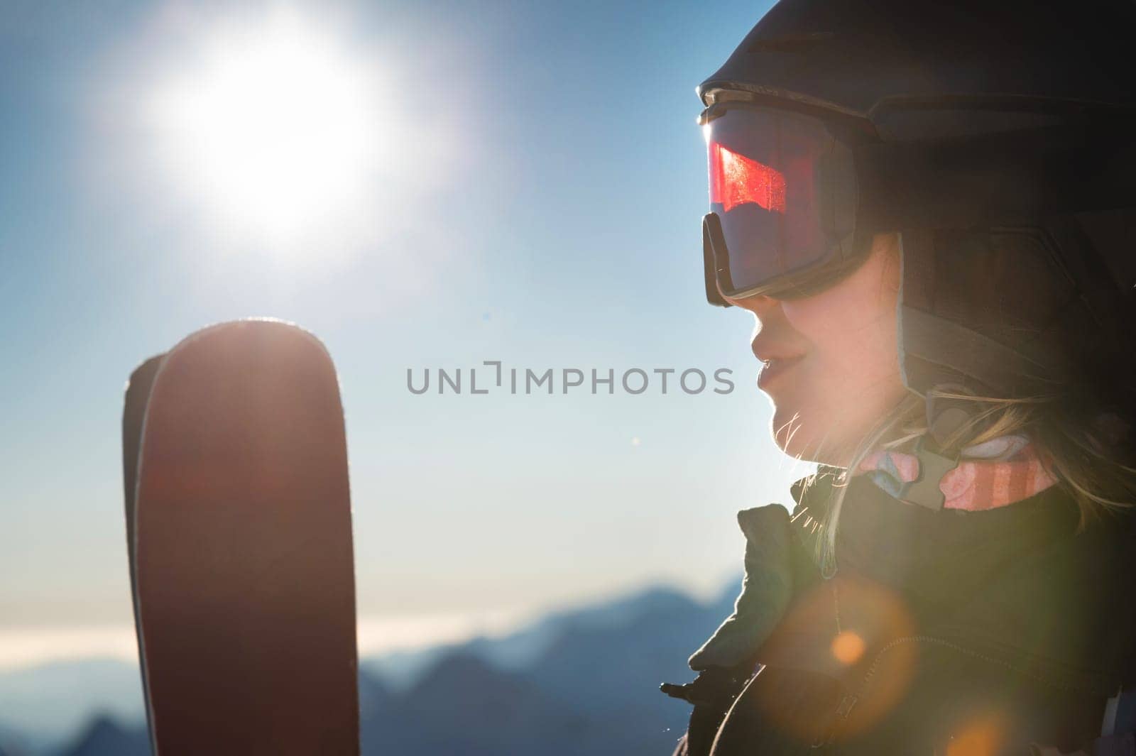 Close-up, ski goggles and a woman's face in a ski resort against the backdrop of mountains and sky on a sunny day by yanik88