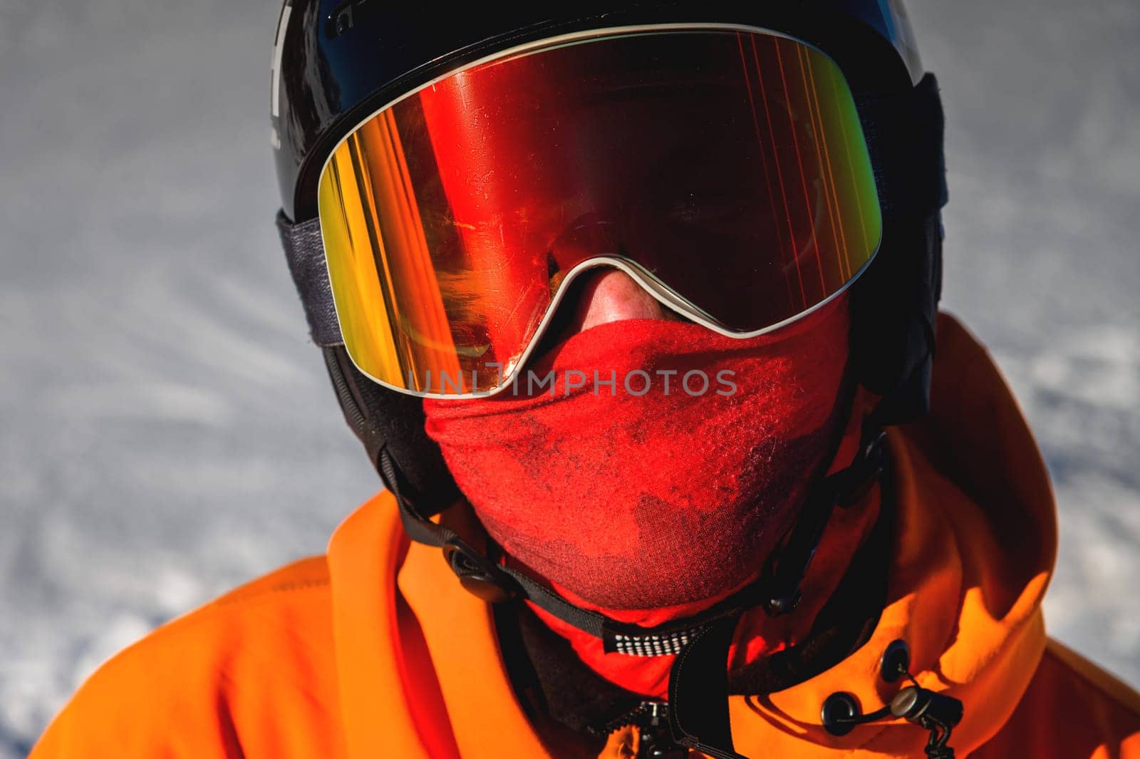 Portrait of a snowboarder. Ski goggles and ski helmet on a man looking at the camera, close-up. Holidays in the ski resort.