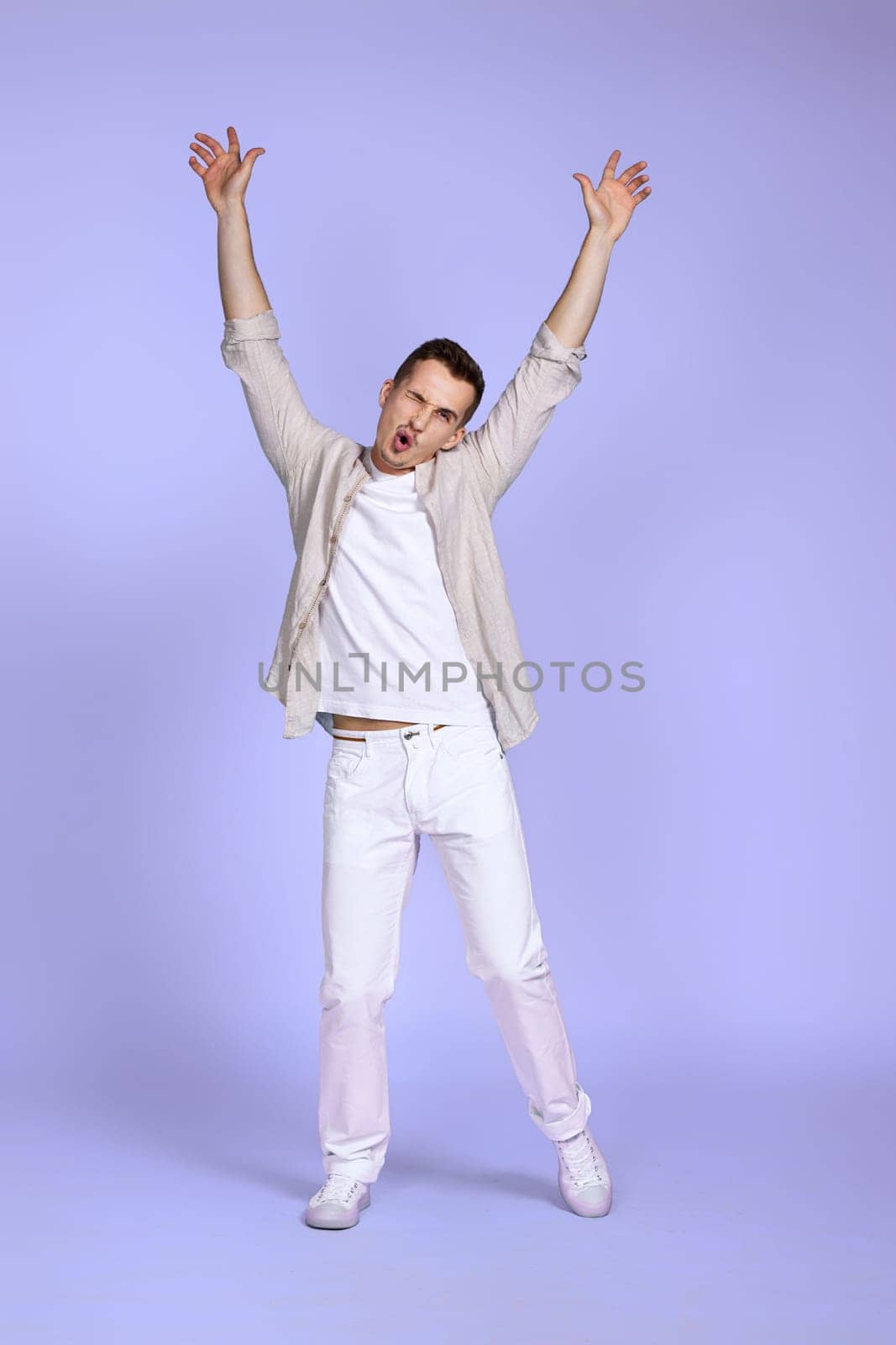 happy funny young man in casual shirt posing isolated on pastel violet background. Having fun, fooling around