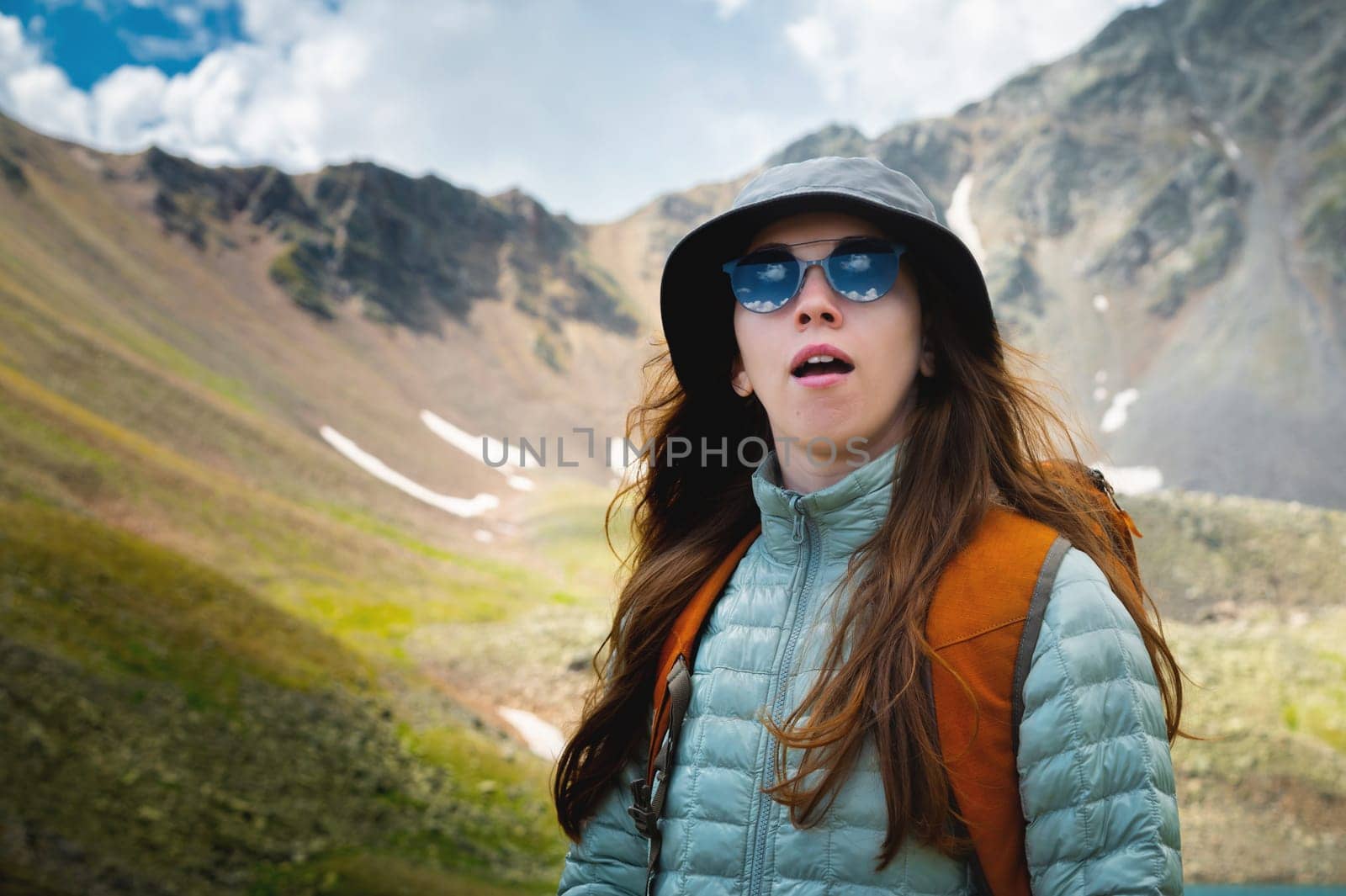 Young beautiful woman yawns. Portrait of a yawning woman on a sunny morning in the mountains. Summer trekking, healthy active lifestyle concept.