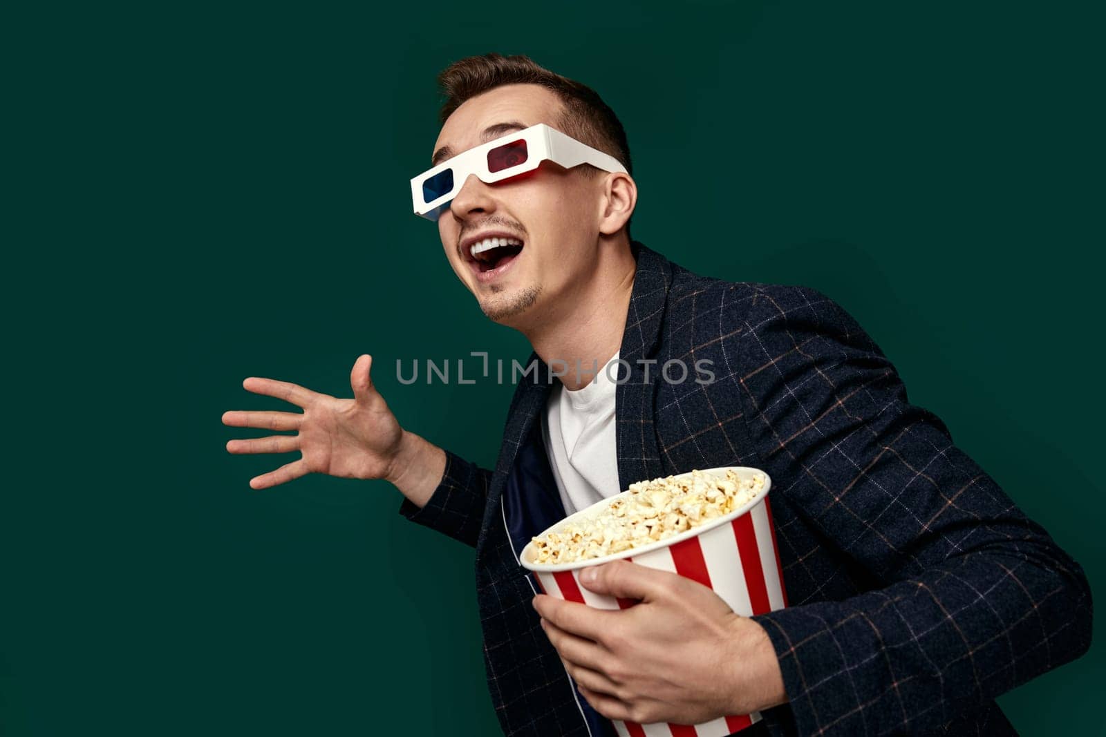 handsome man in 3d glasses and plaid jacket with popcorn on green background.