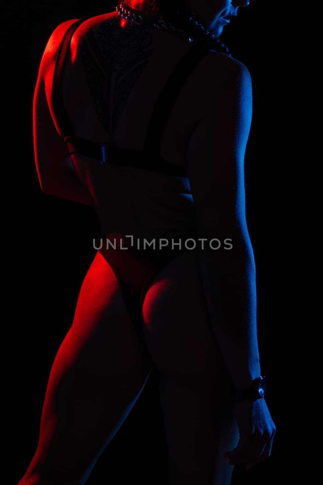 Beautiful female body on dark background in a red blue neon light. Fit and sportive, sensual.