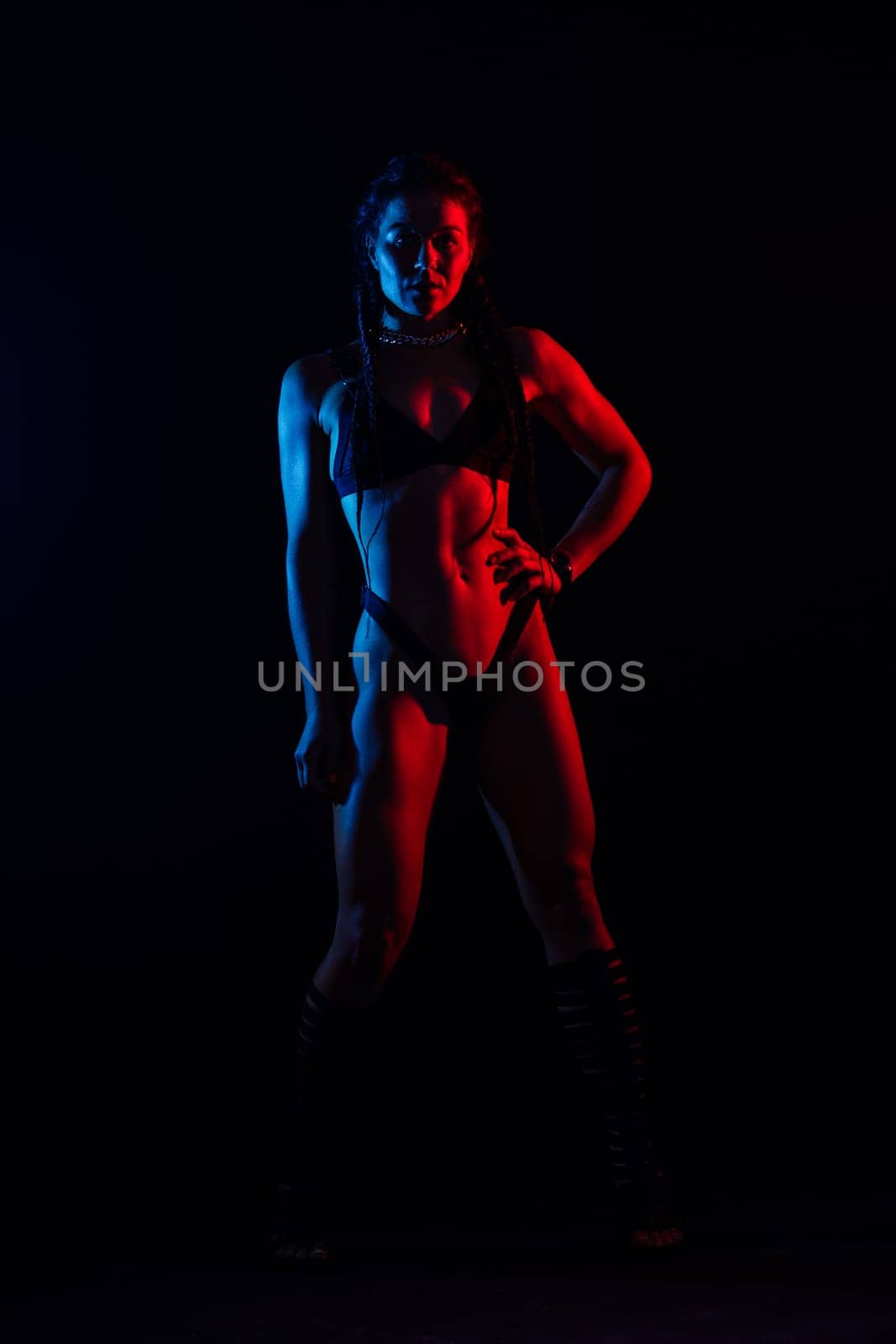 Beautiful female body on dark background in a red blue neon light. Fit and sportive, sensual.