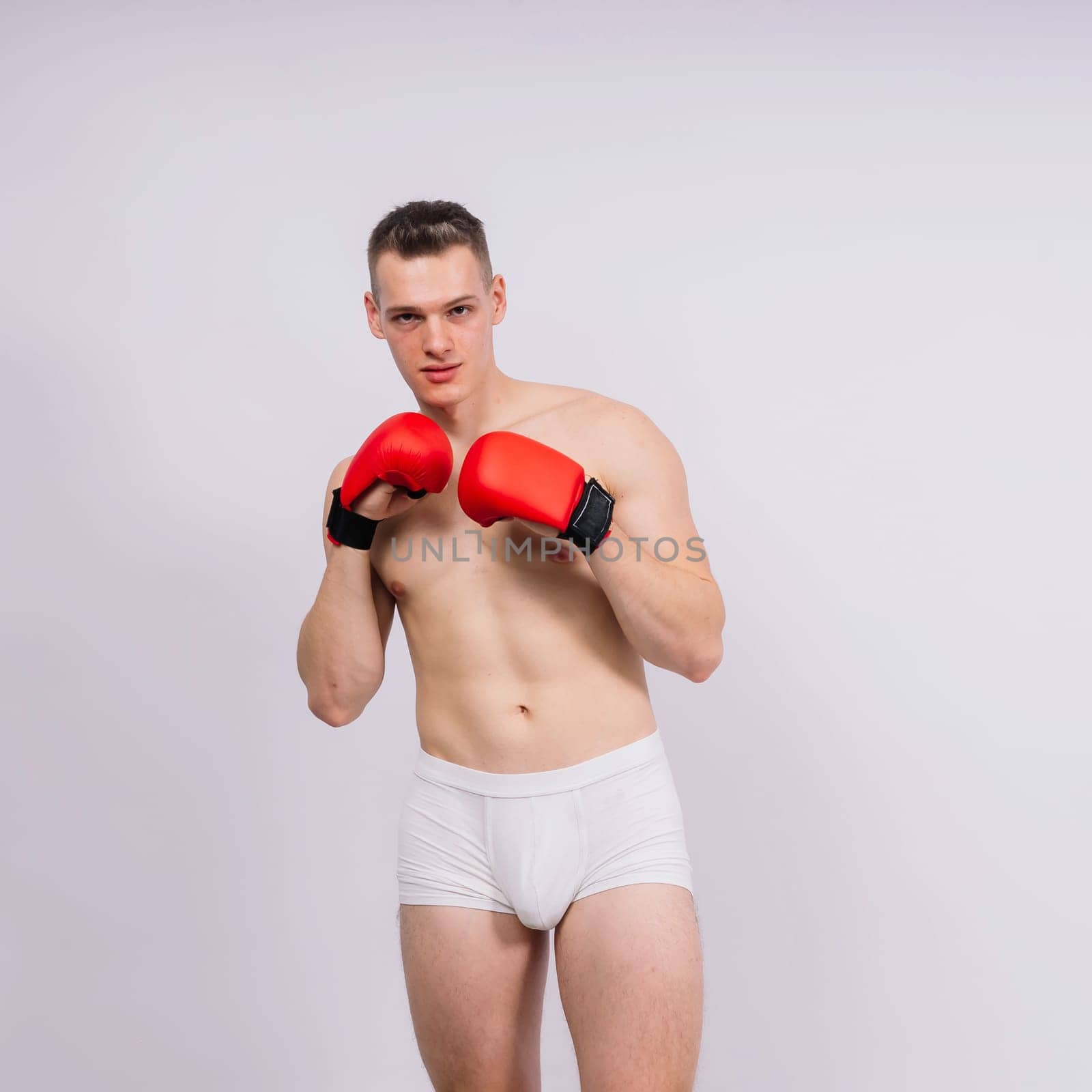 Bodybuilders boxing gloves on a white background and white pants athlete model