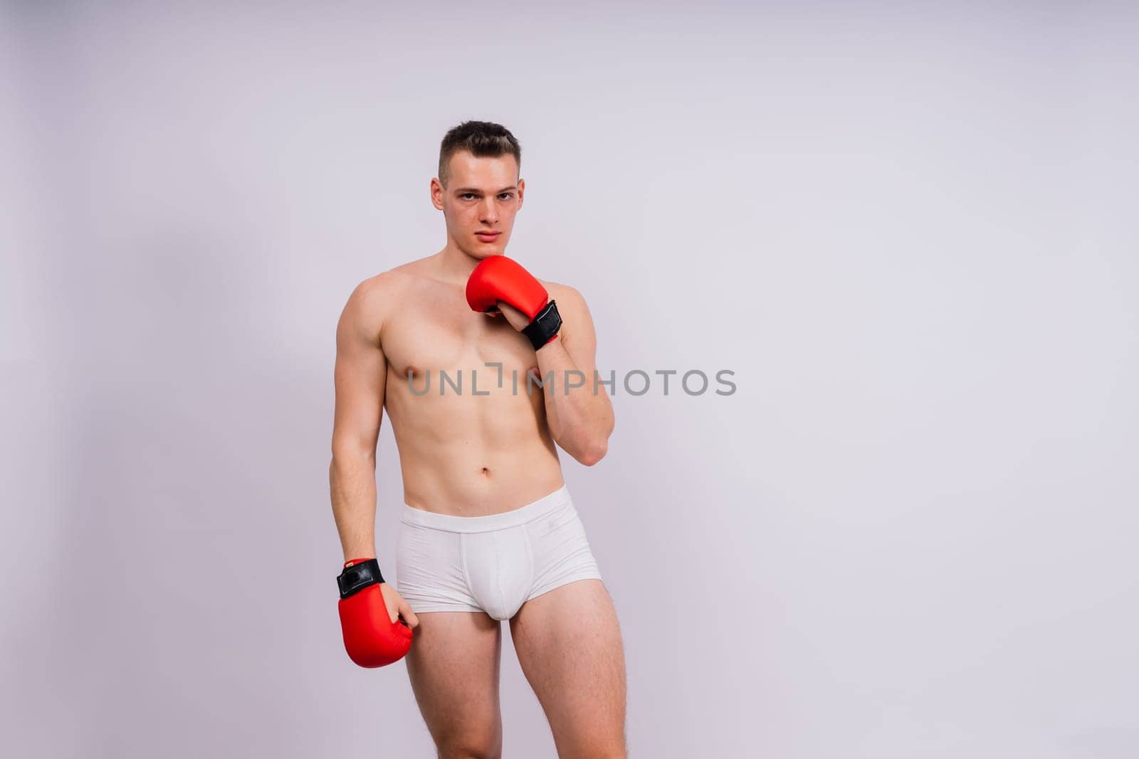 Bodybuilders boxing gloves on white background and white pants athlete model by Zelenin