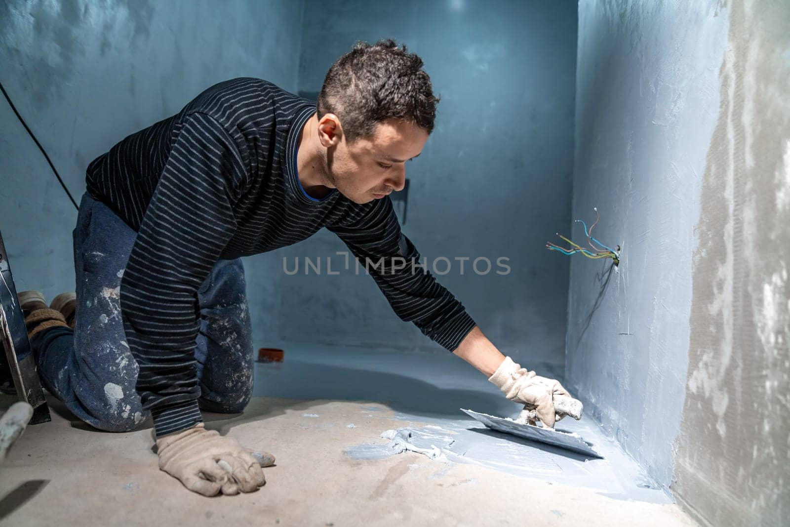 bricklayer works with trowel in room. High quality photo