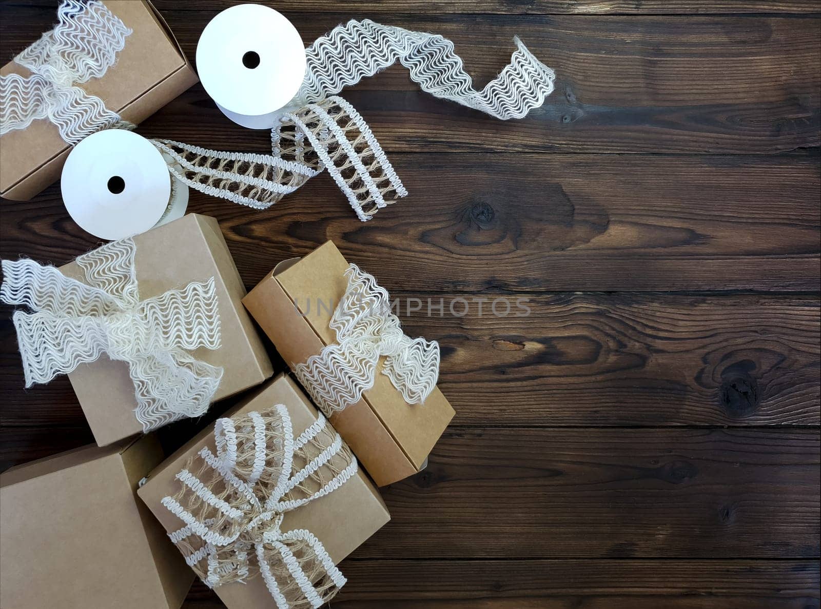 On a wooden table there are craft boxes decorated with bows. by Spirina