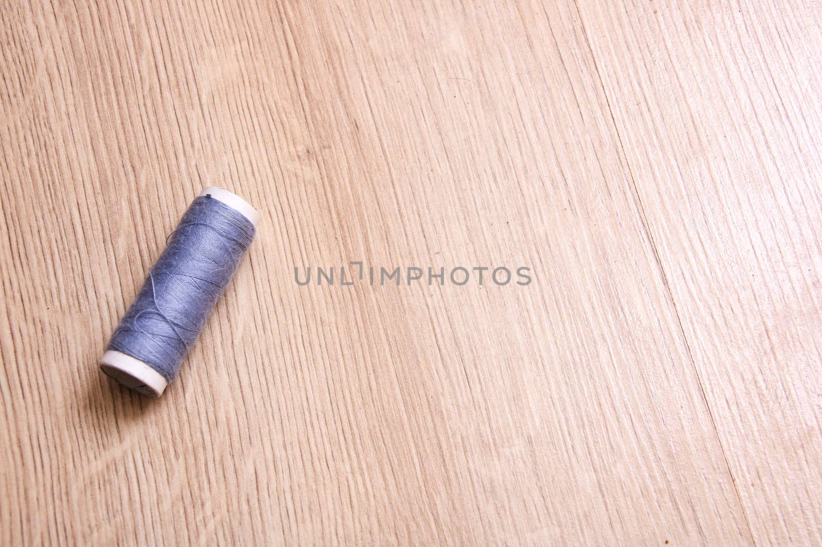 Coil of grey thread on a wooden table close up