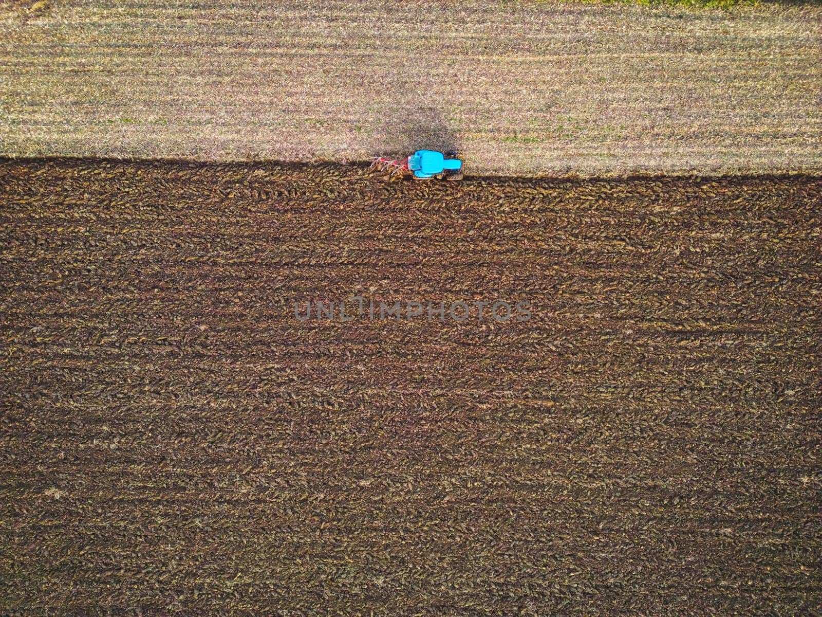 Aerial view of a tractor ploughing a field, a farmer in a modern tractor ploughing field on a sunny day. High quality photo
