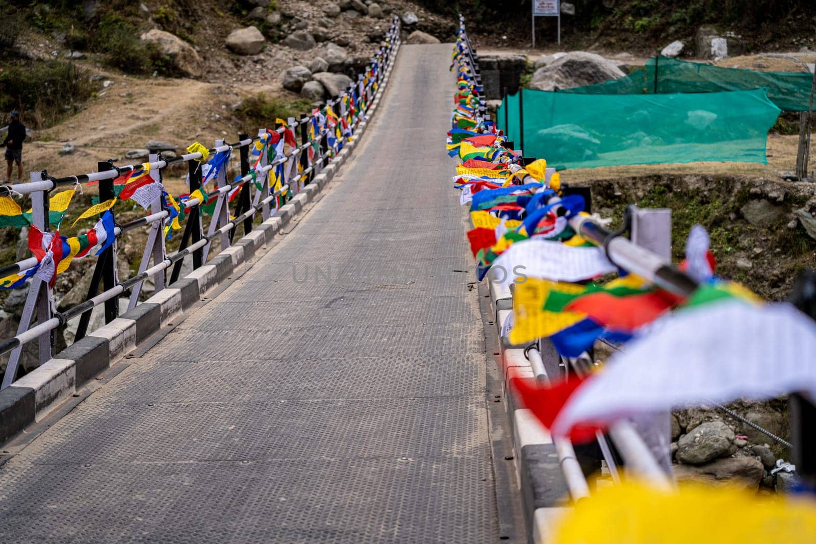 Sacred religious multicolored prayer flags placed on both sides of bridge moving in the wind showing a bhuddist prayer incantation common in hill stations in Himachal Pradesh by Shalinimathur